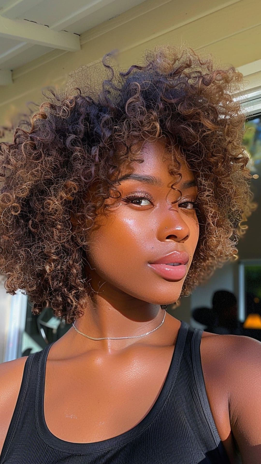 A black woman modelling a golden brown afro hair.