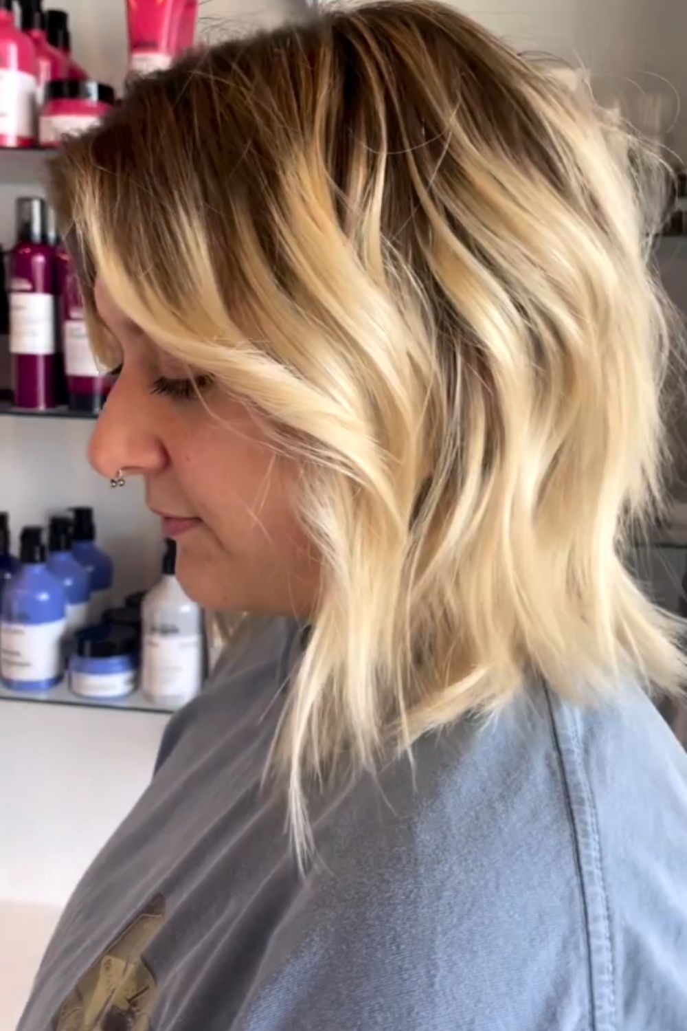 A woman with a blonde feathered bob with shadow roots.