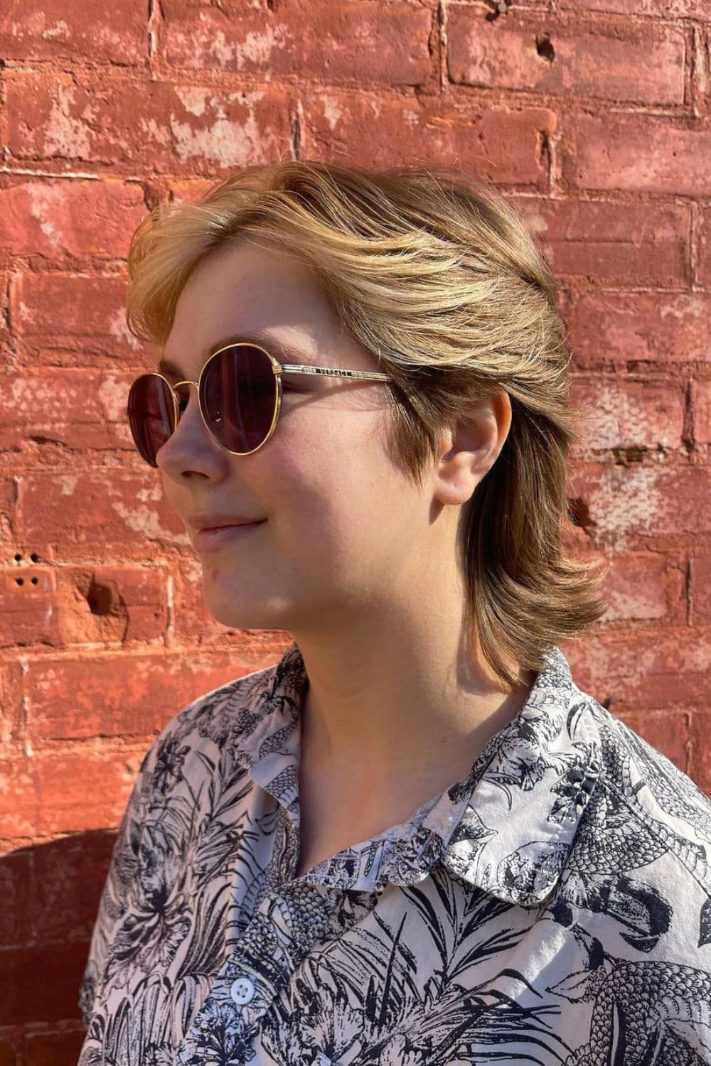 A woman wearing sunglasses with a blonde 80s feather cut.