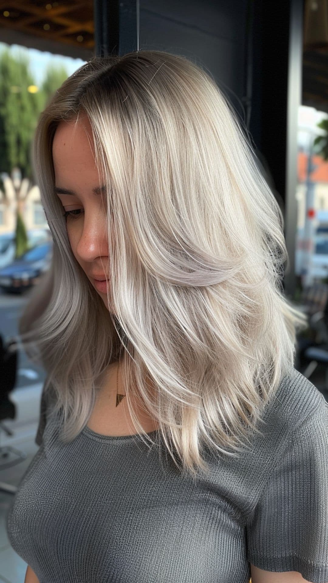 A woman modelling an ash blonde hair with dark roots.