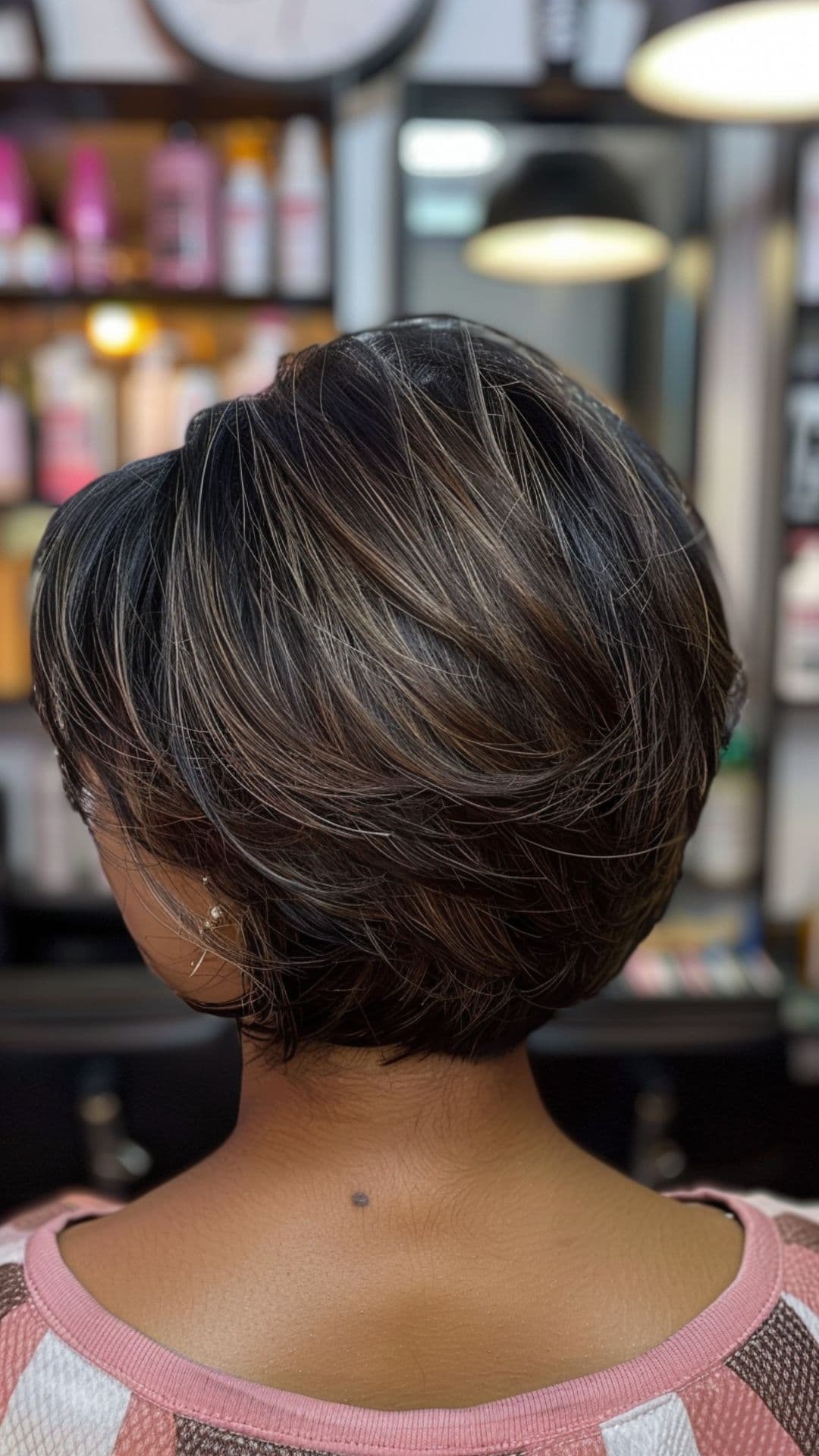 A woman with dark skin tone modelling an ash brown hair.