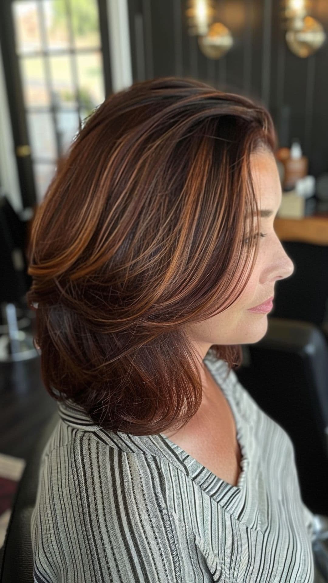 A woman modelling an auburn highlights on short hair.