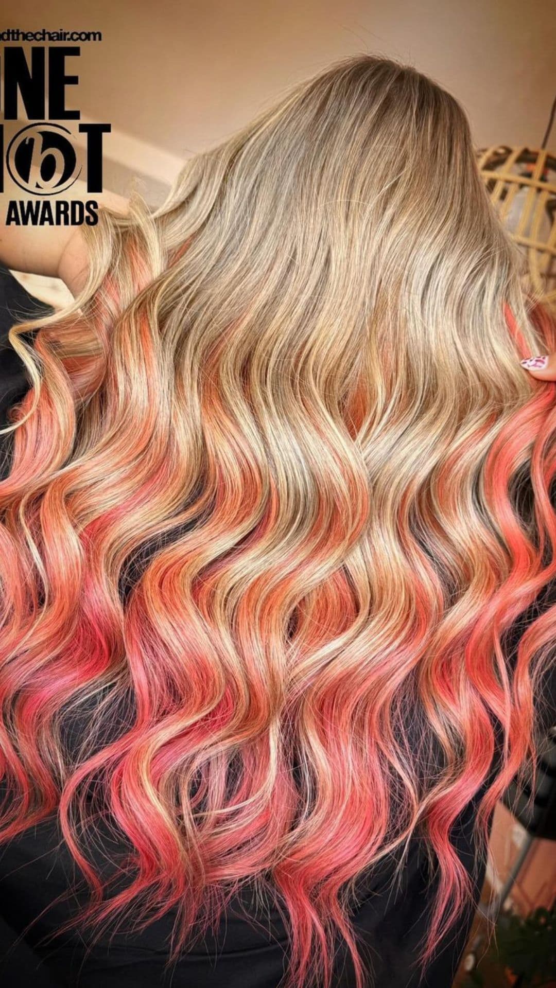 A woman modelling a blonde to peachy coral pink ombre.