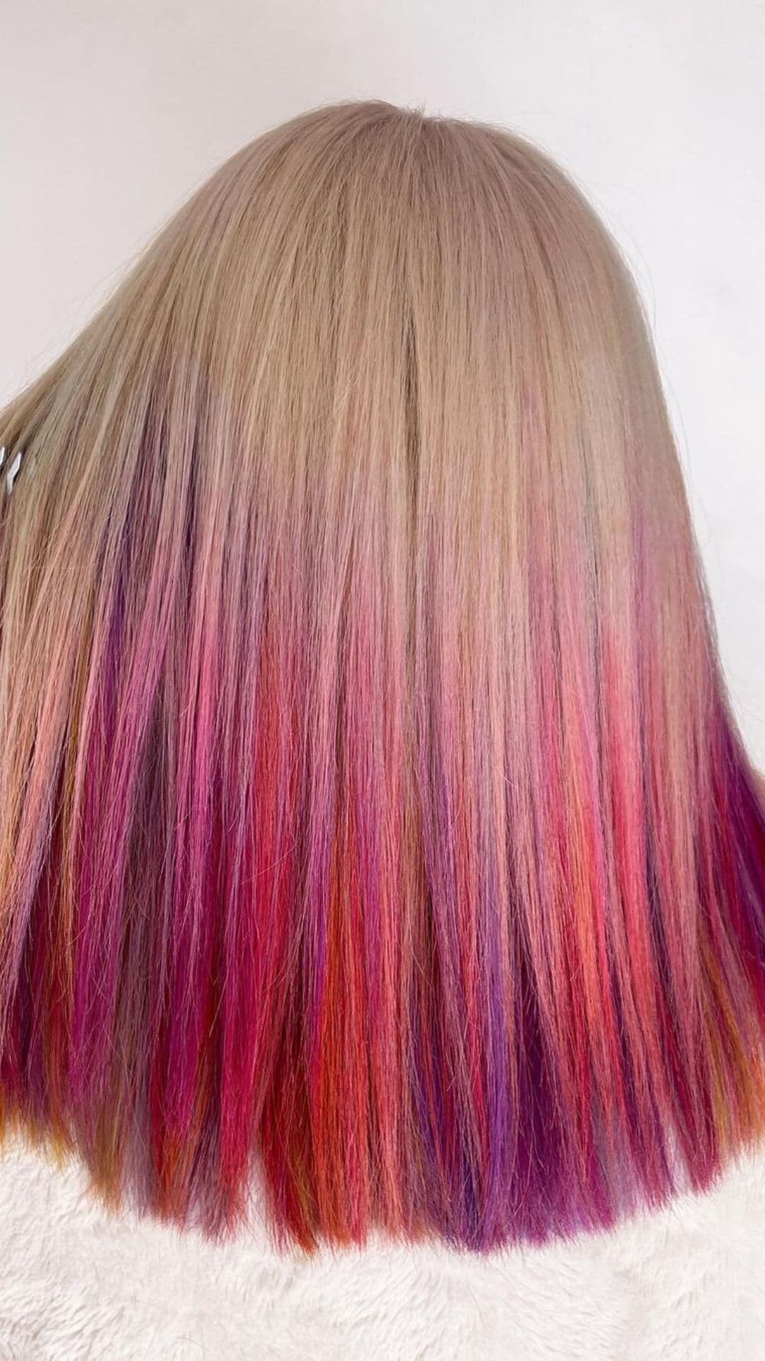 A woman modelling a blonde to unicorn hair ombre.