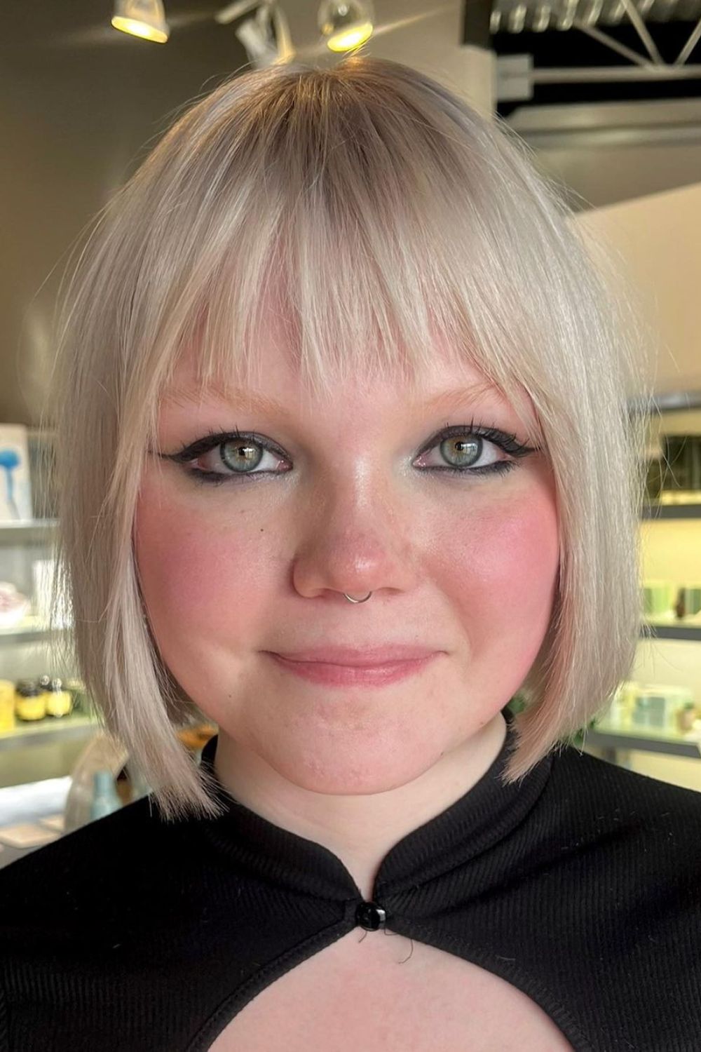 A woman with a blonde chin-length bob cut with wispy bangs.