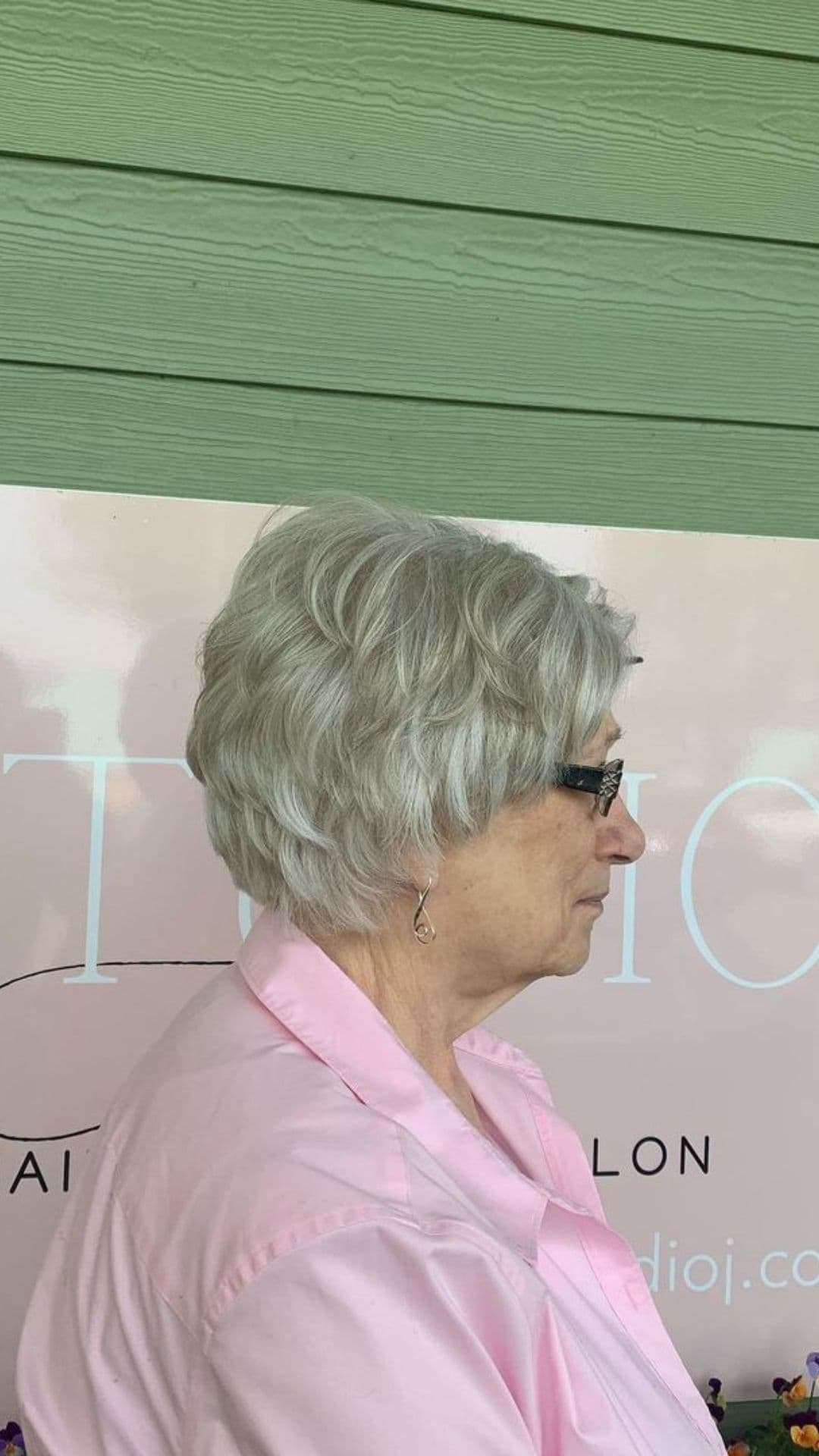 An older woman modelling a choppy neck-length gray hairstyle.