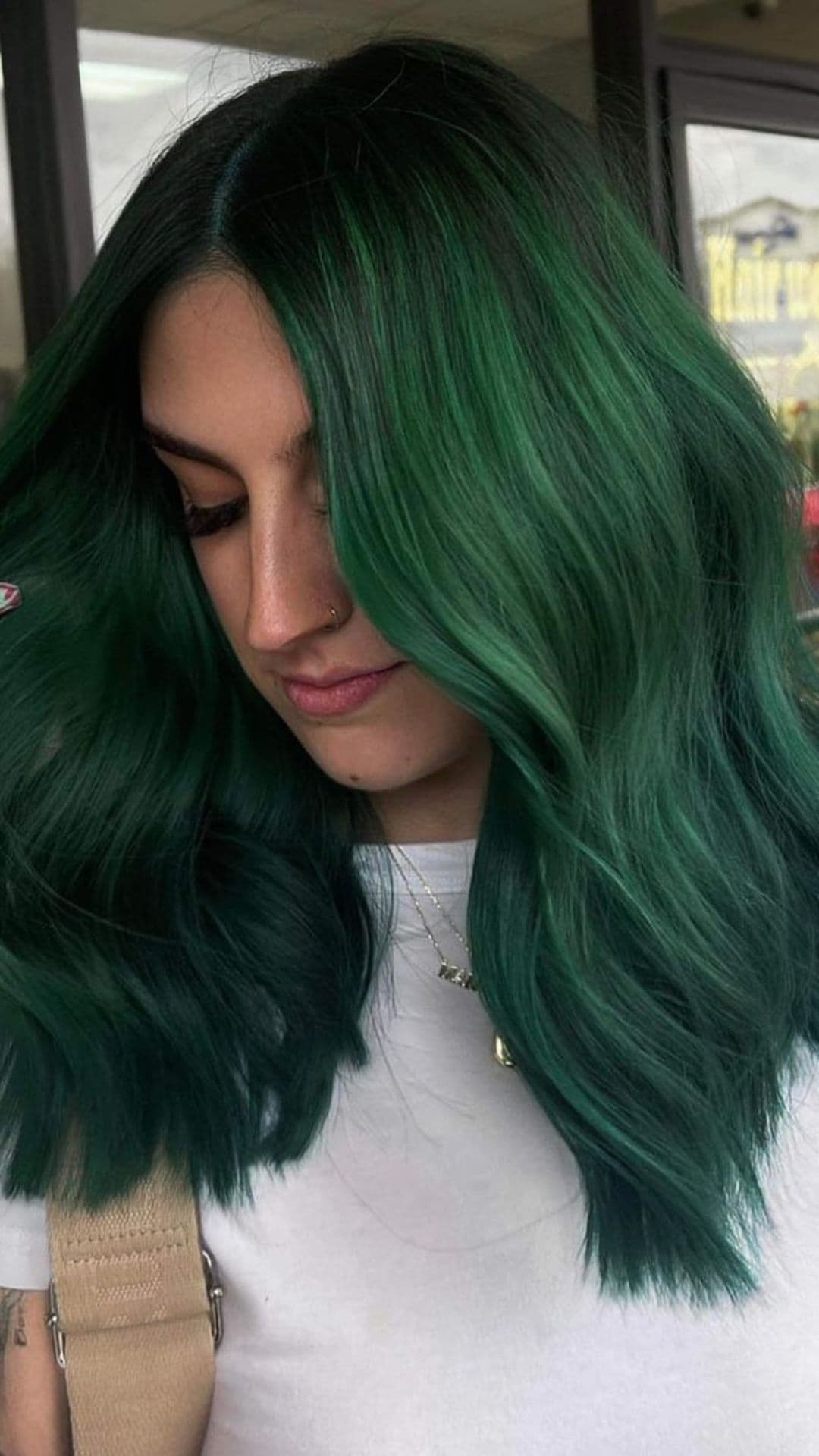 Person with shoulder-length Emerald Green hair wearing a white top.