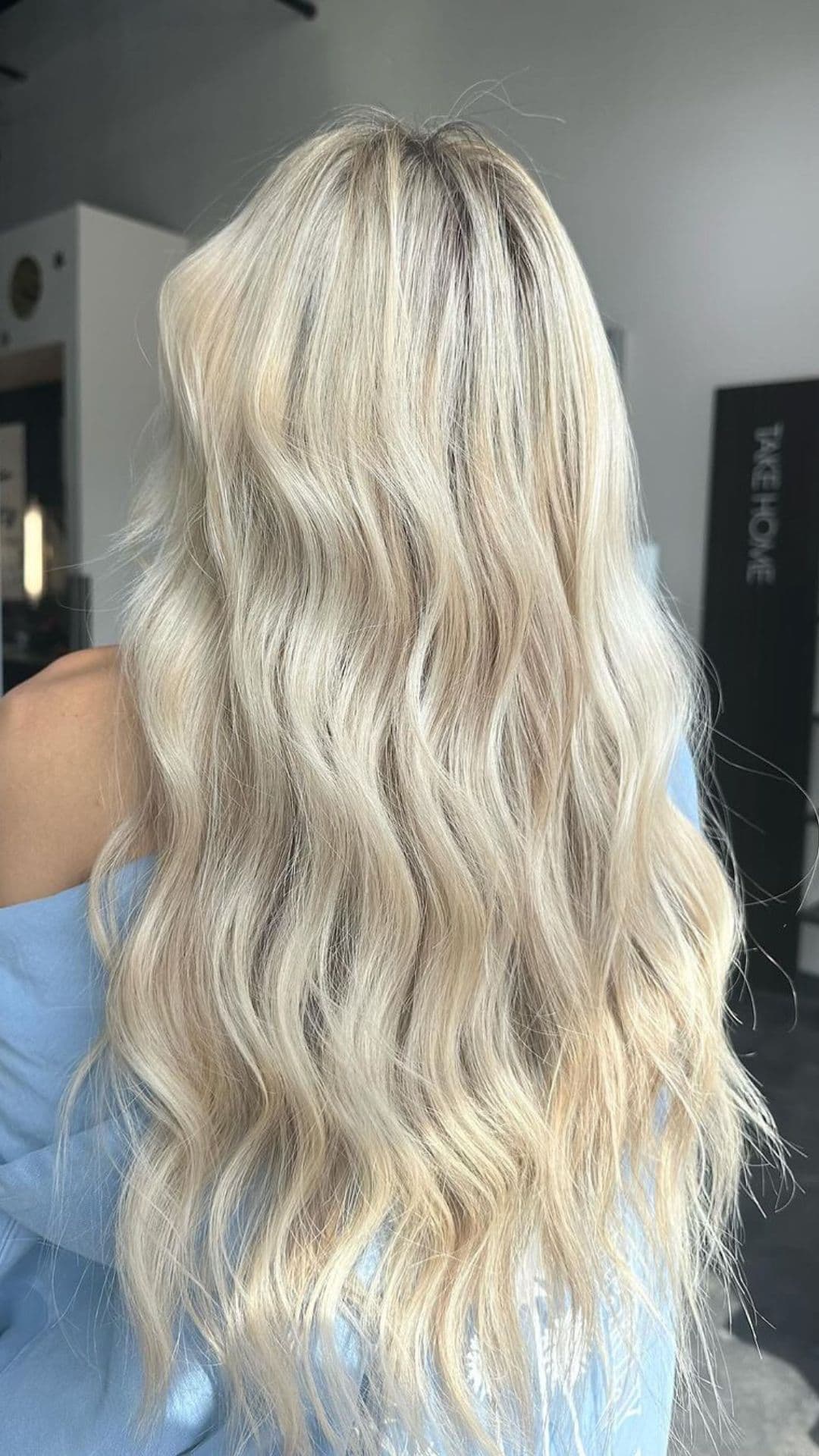 Back view of person with long, wavy Icy Blonde hair. The hairstyle features soft, flowing curls.