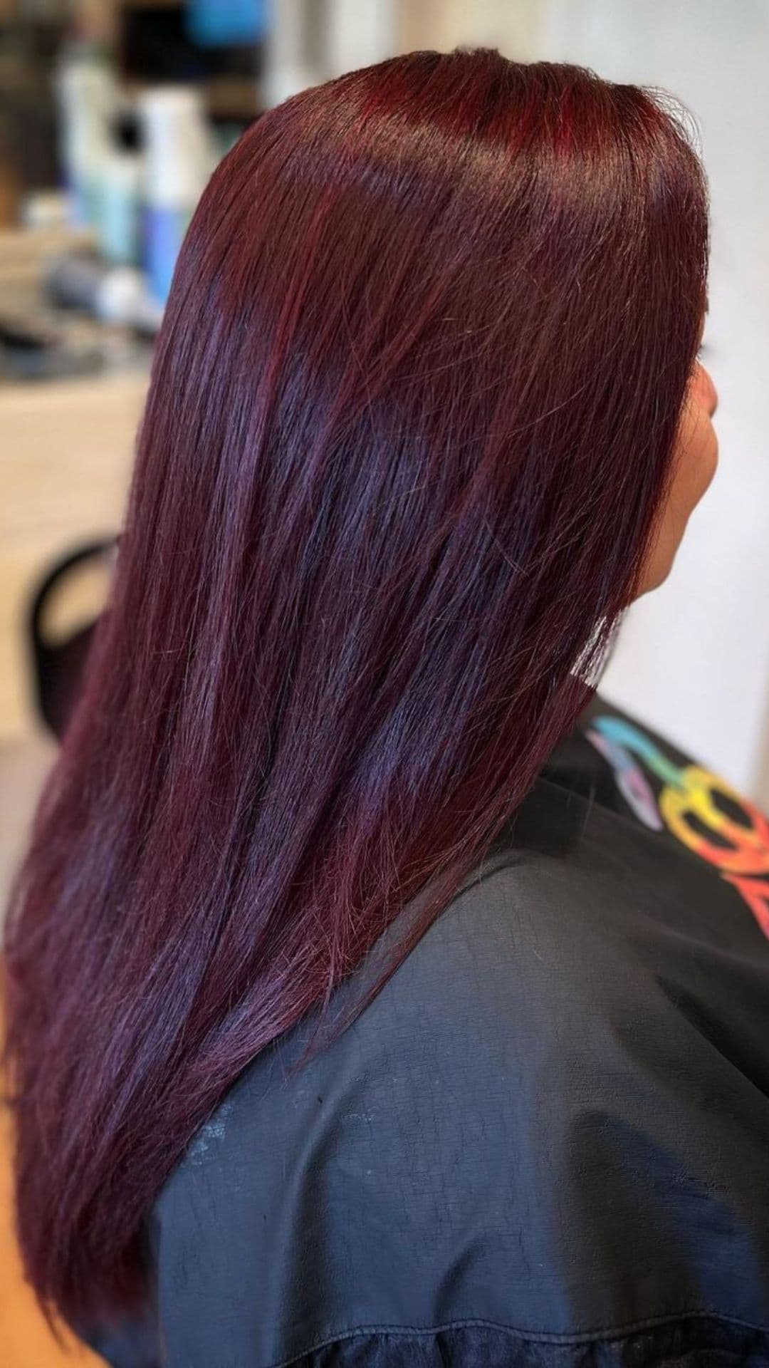 Woman showcasing Mulled Wine hairstyle with long, smooth, deep red hair.