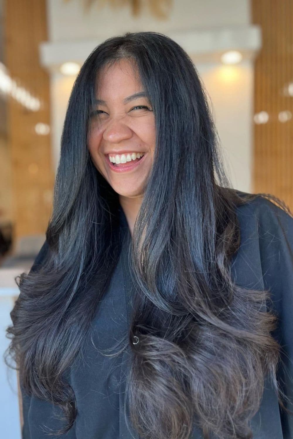 A happy woman with black, classic long face-framing layers.