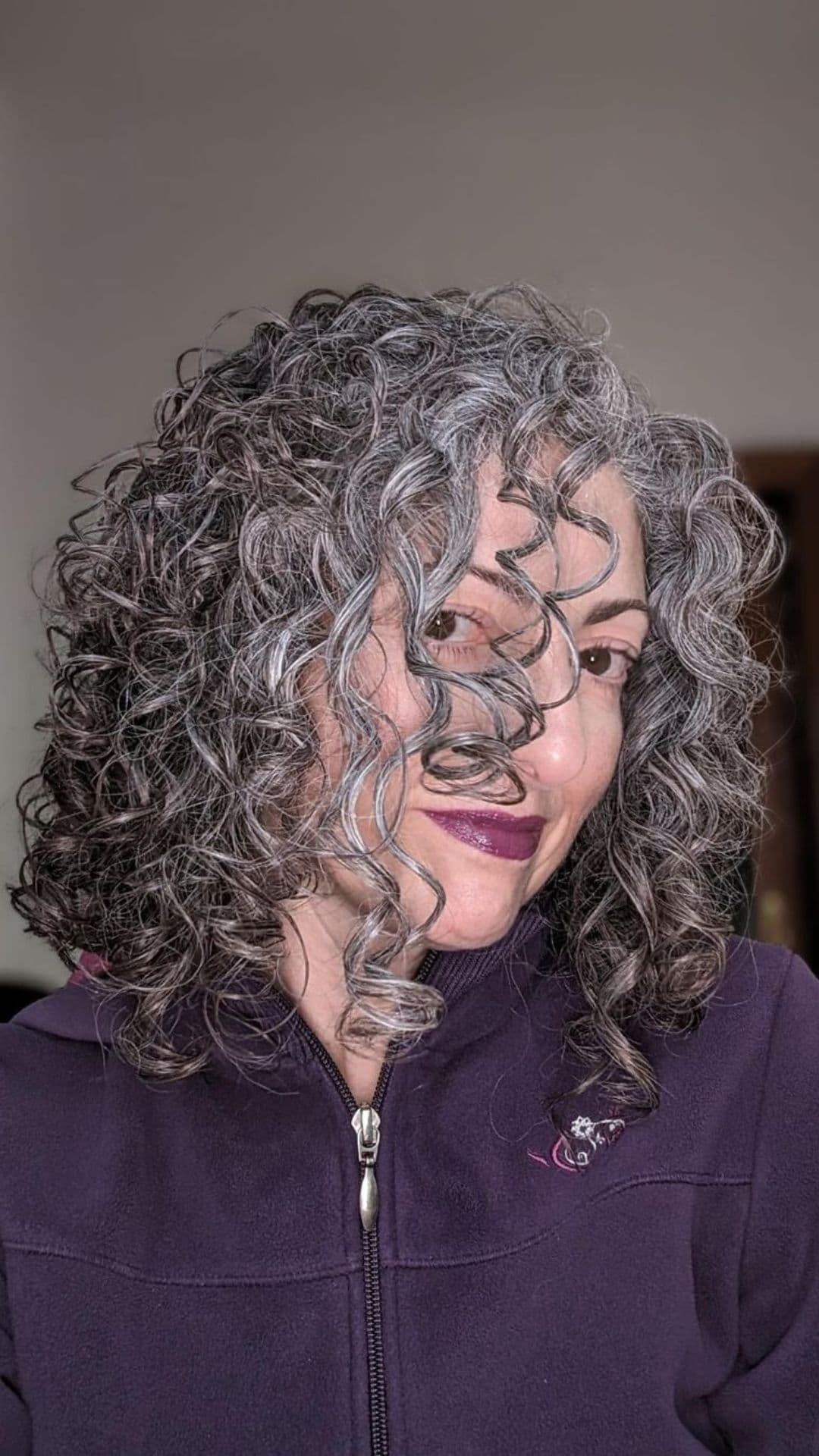 An older woman modelling a curly gray hair.