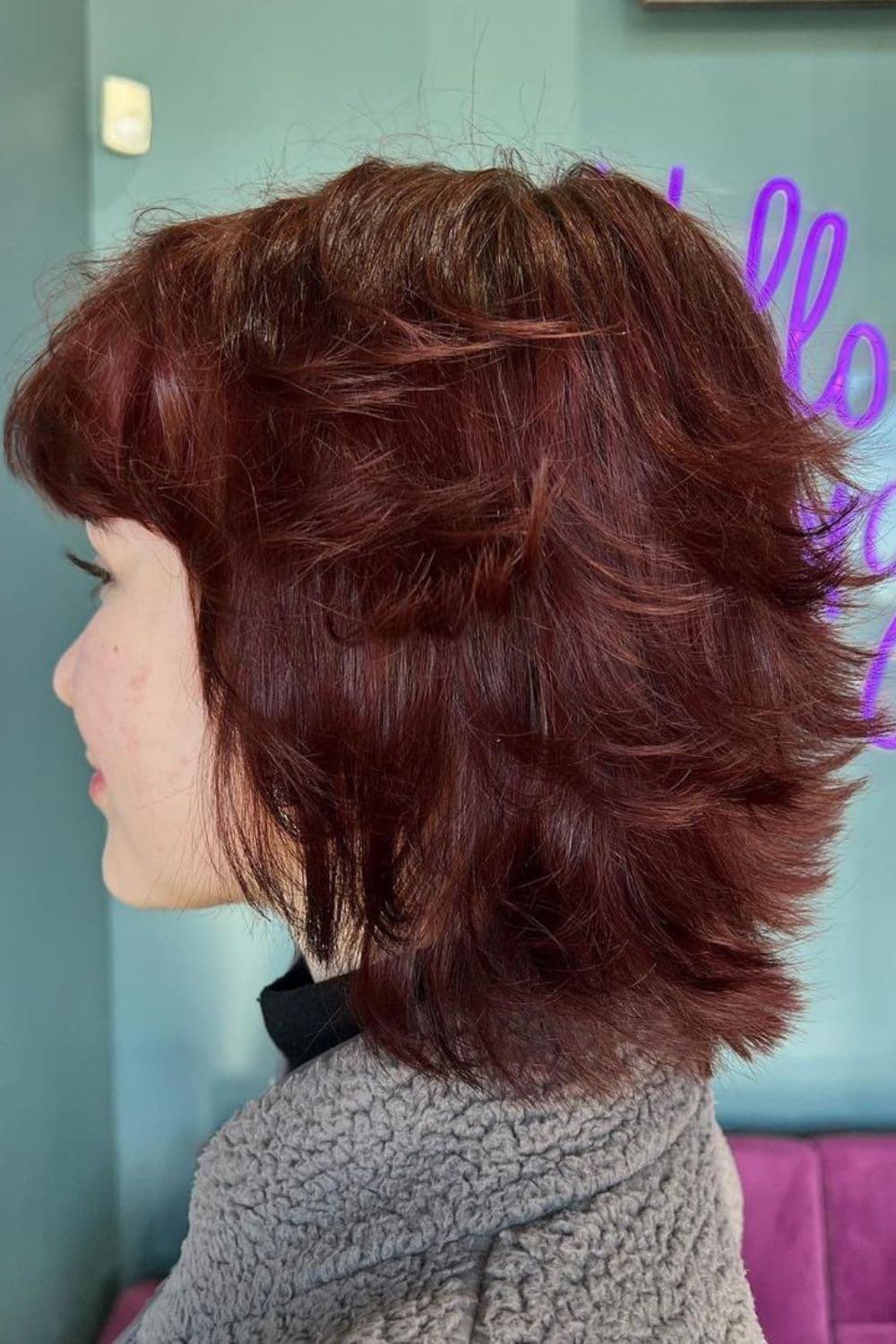 A woman with an auburn feathered cut with bixie cut.