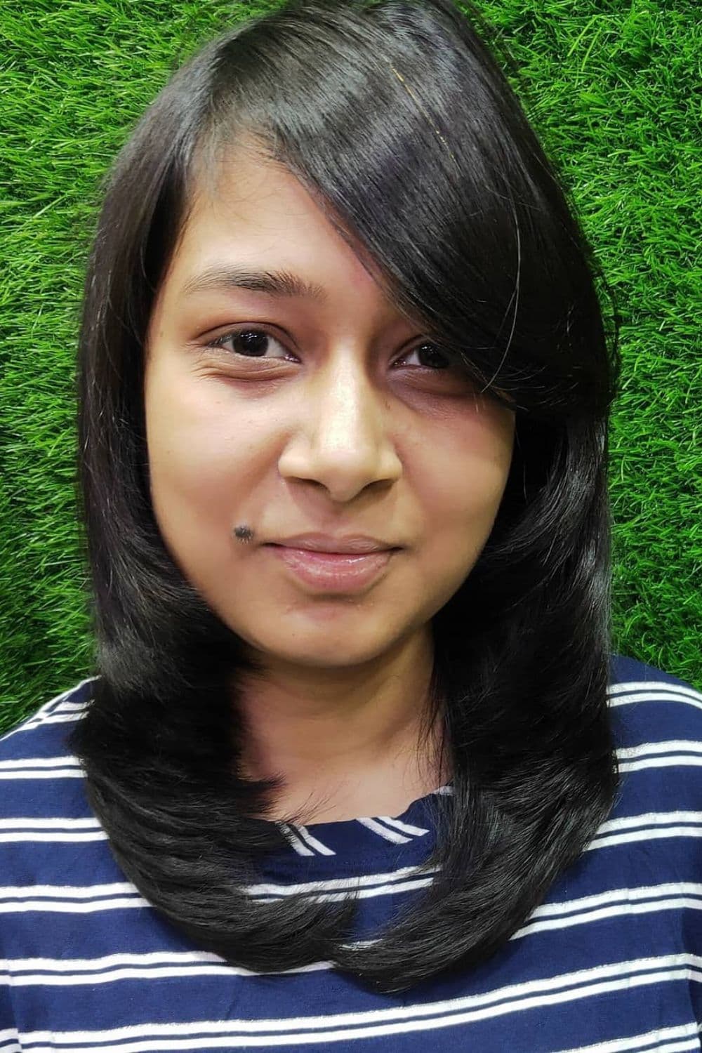 A woman with a black feathered cut with side bangs.