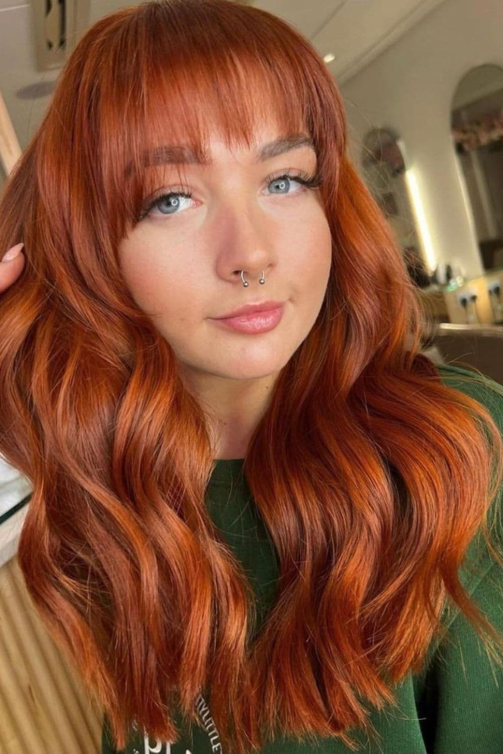 A woman with a ginger feathered cut with wispy bangs.