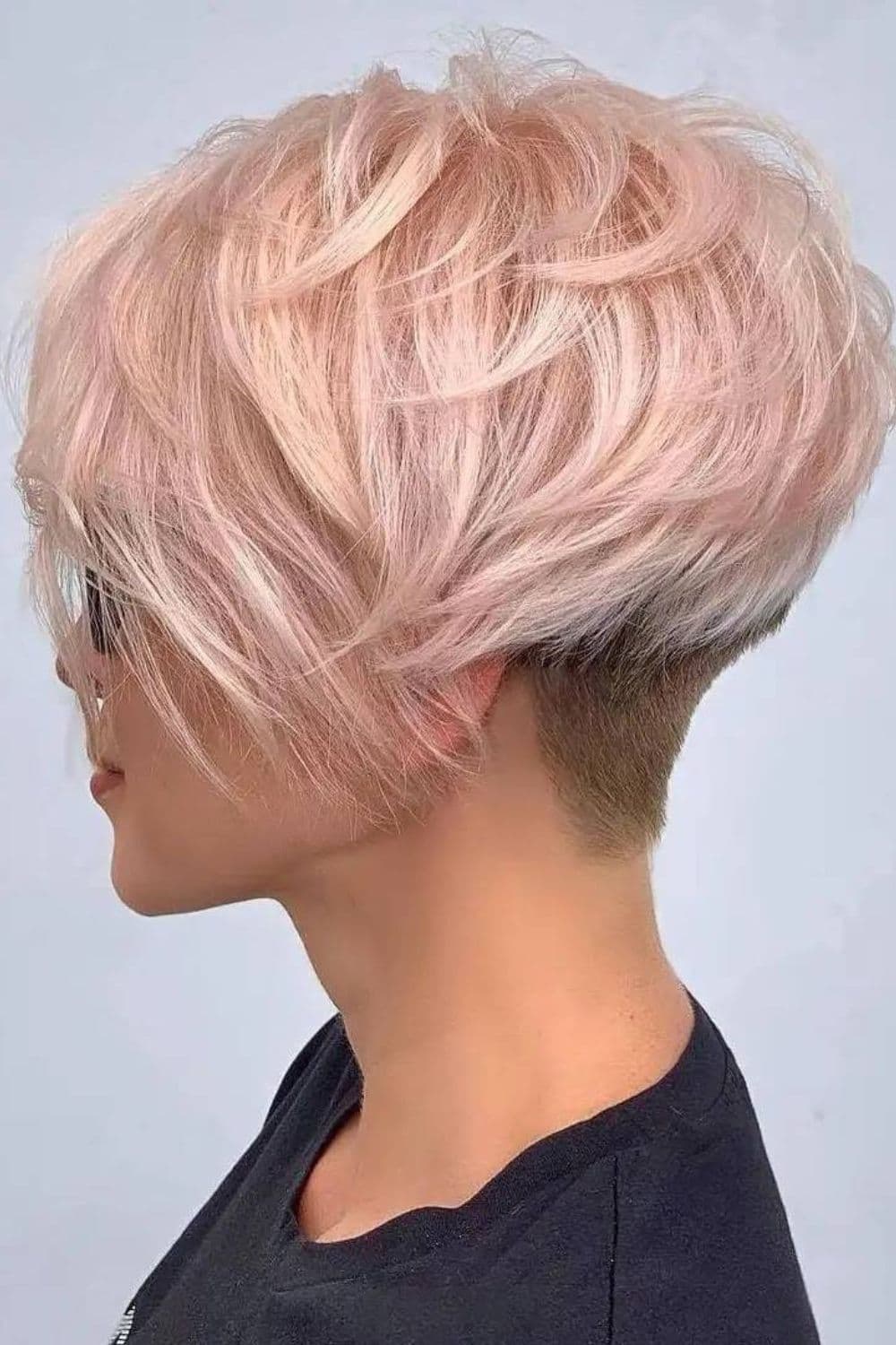 A woman with a light pink feathered pixie with an undercut.