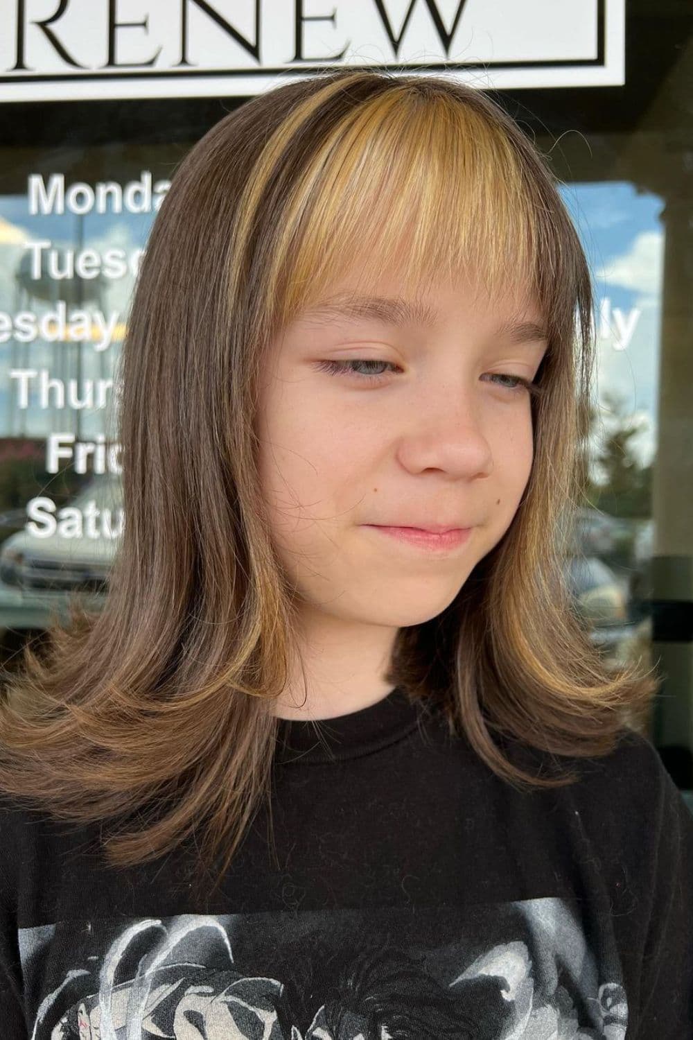 A girl with brown flipped-out layers with blonde bangs.