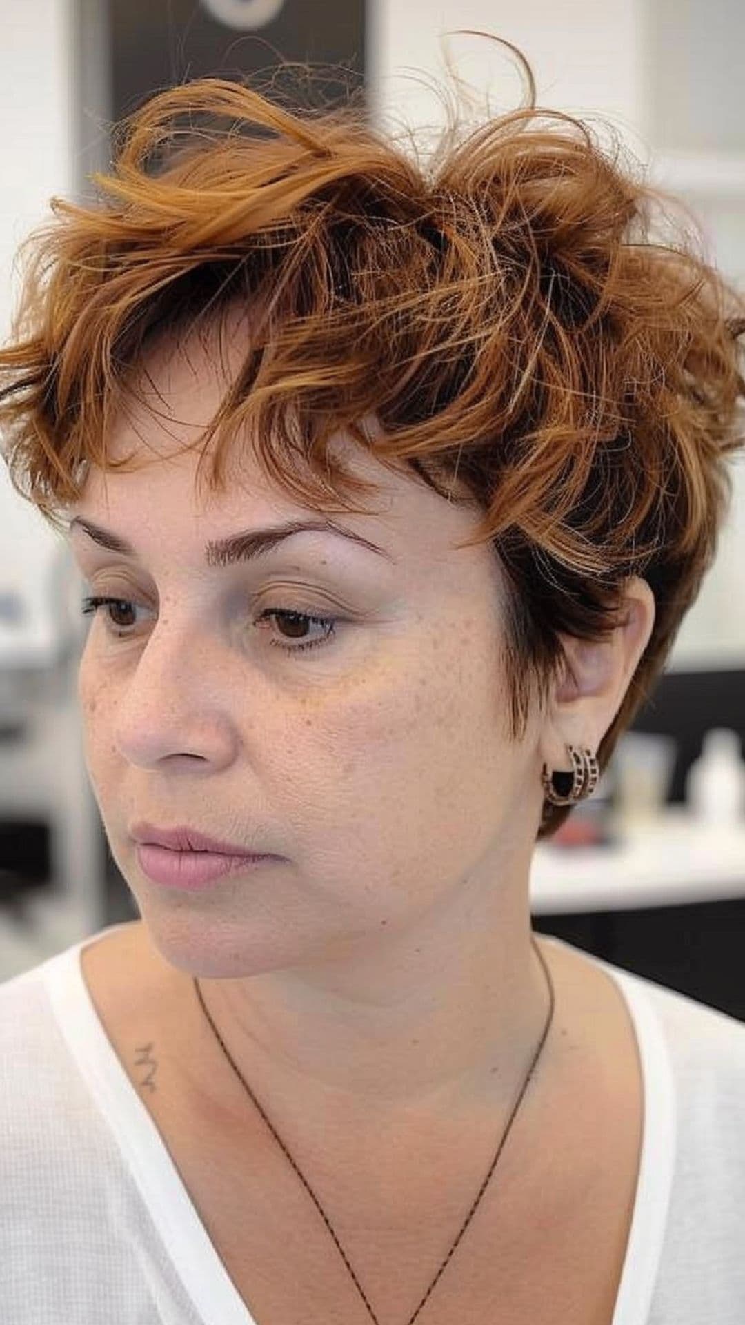 A woman modelling a ginger balayage tousled pixie cut.