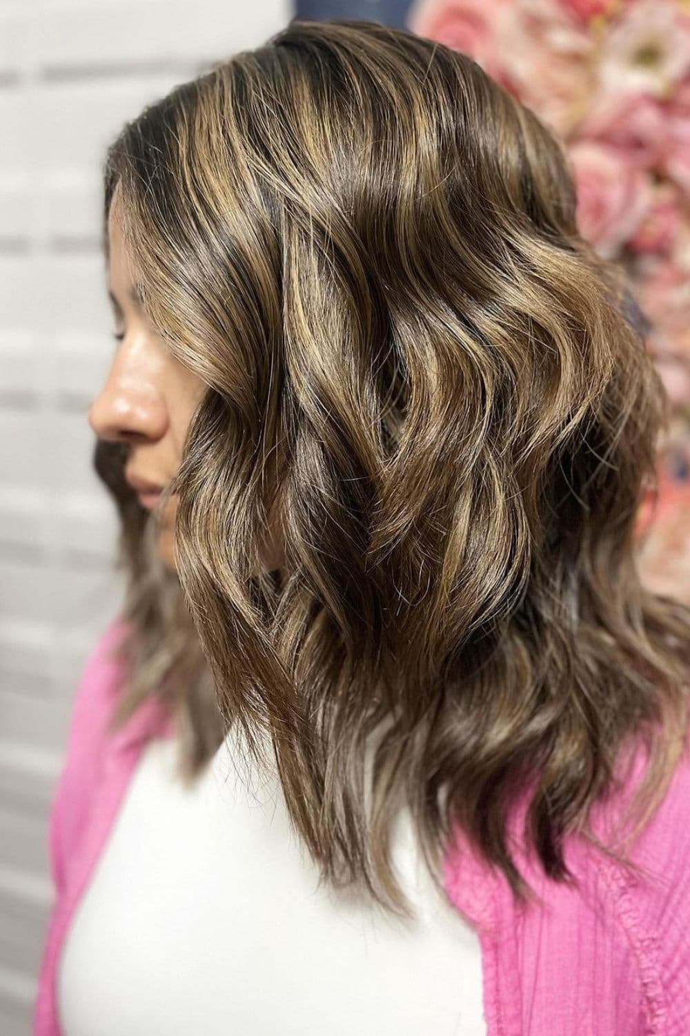 Side view of a woman with layers and blonde balayage.