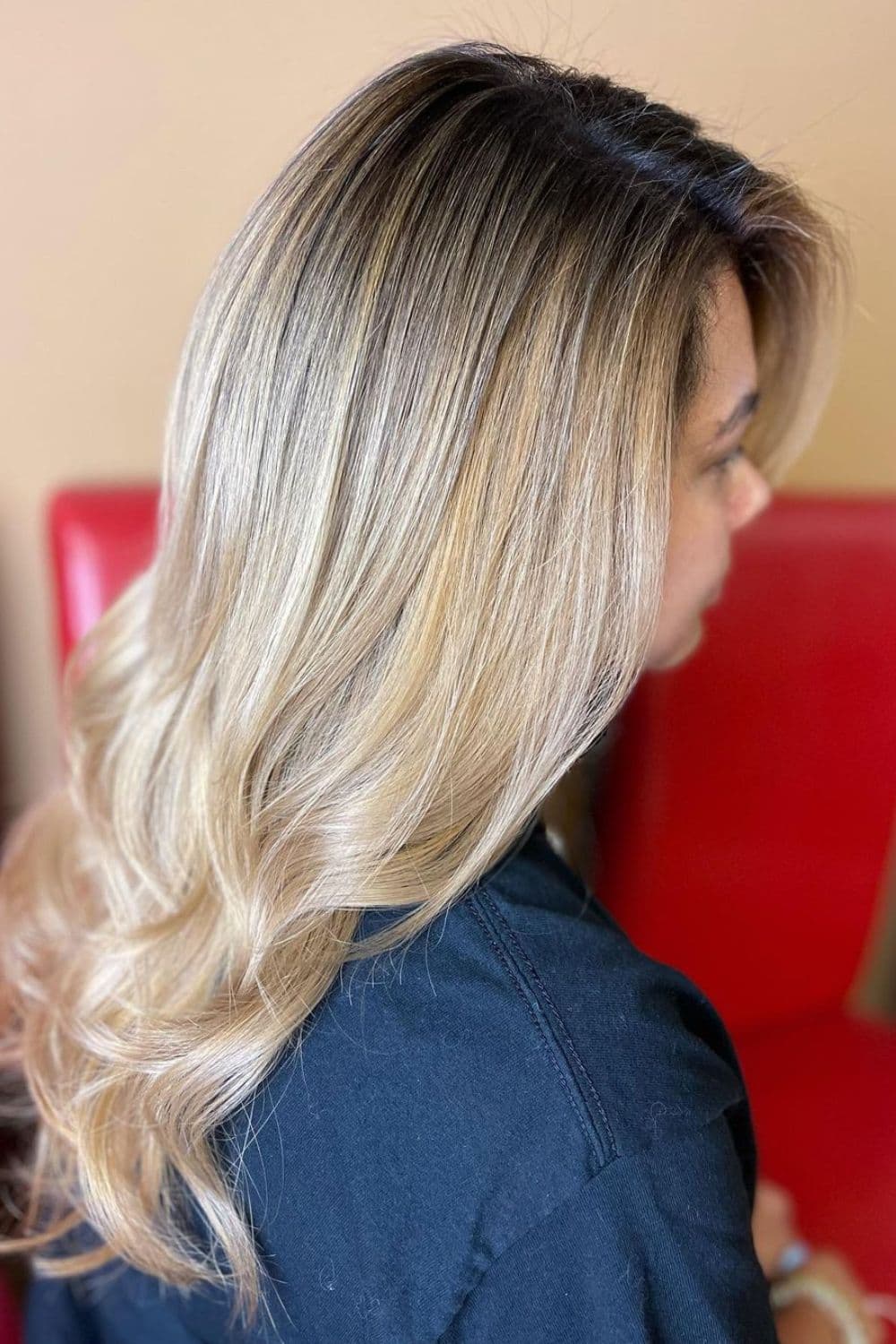 Side view of a woman with long blonde layers with shadow root.