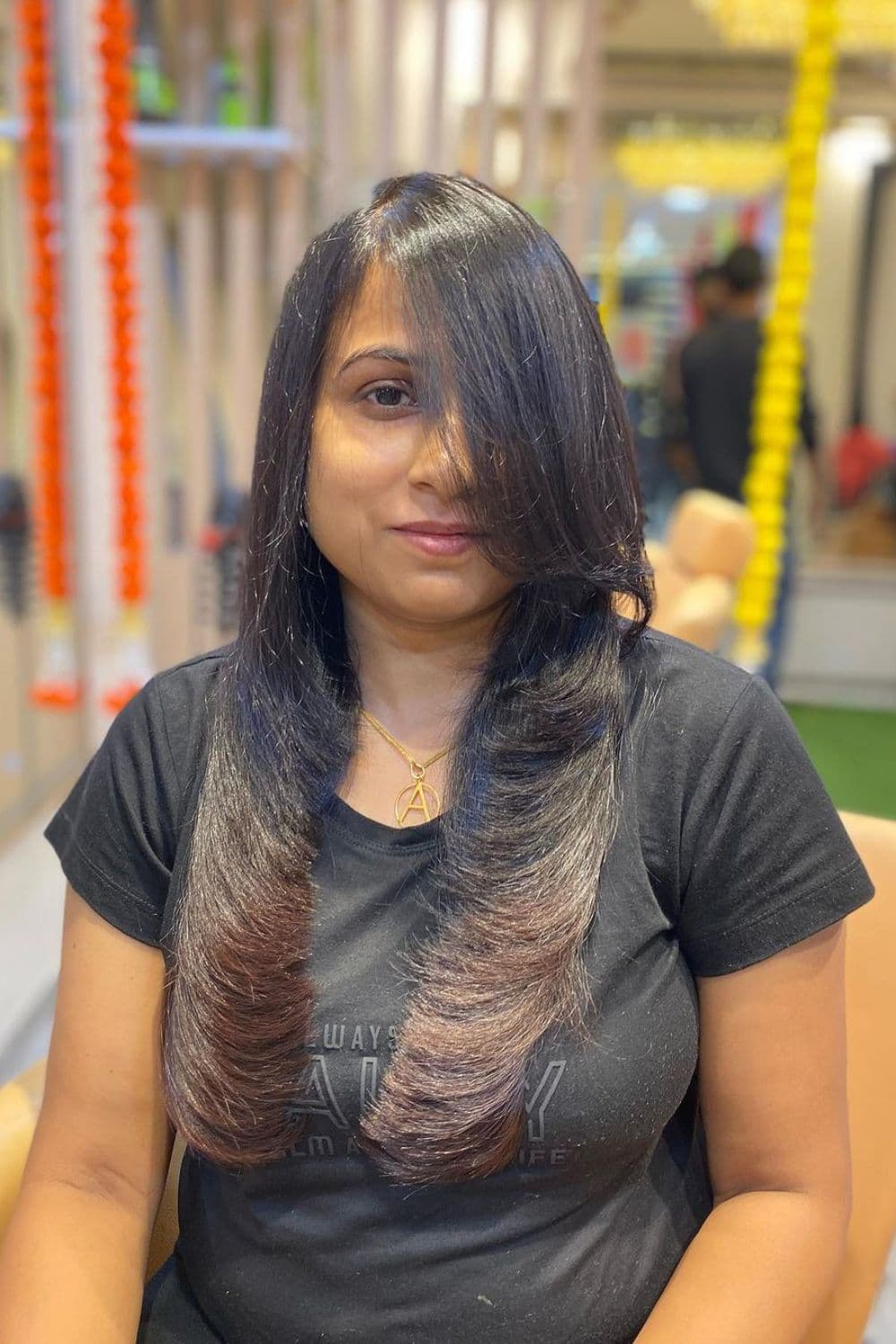 A woman with a long black feather cut and brown ombre.