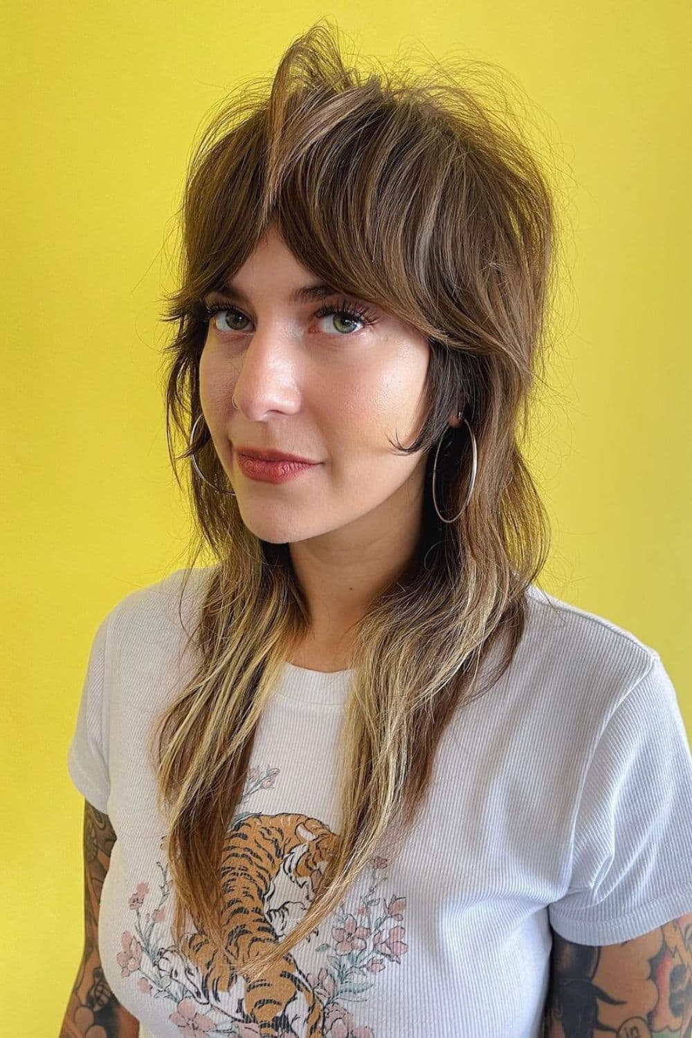 A woman with a long shaggy razor cut with curtain bangs.