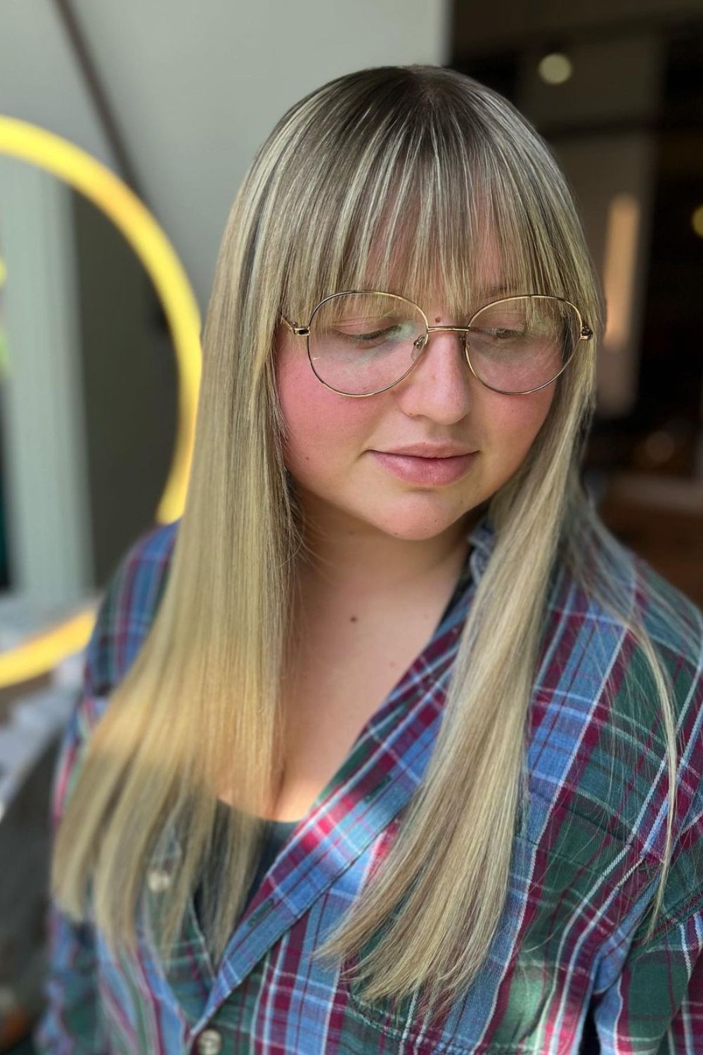 A woman with long blonde straight hair with full bangs.