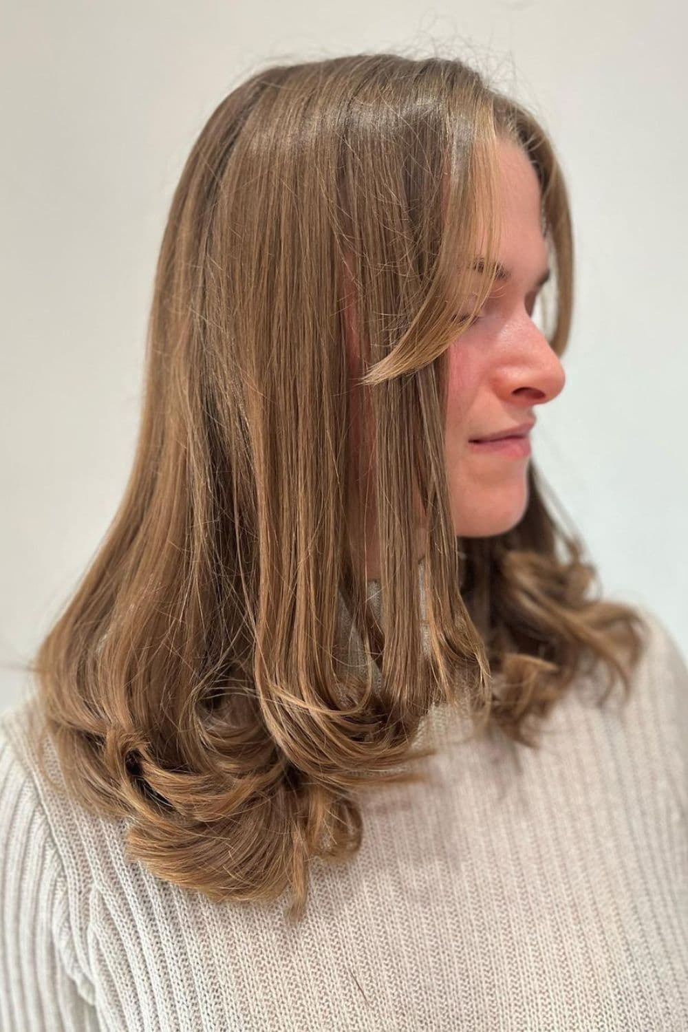 A woman with a light brown medium-length feathered cut.