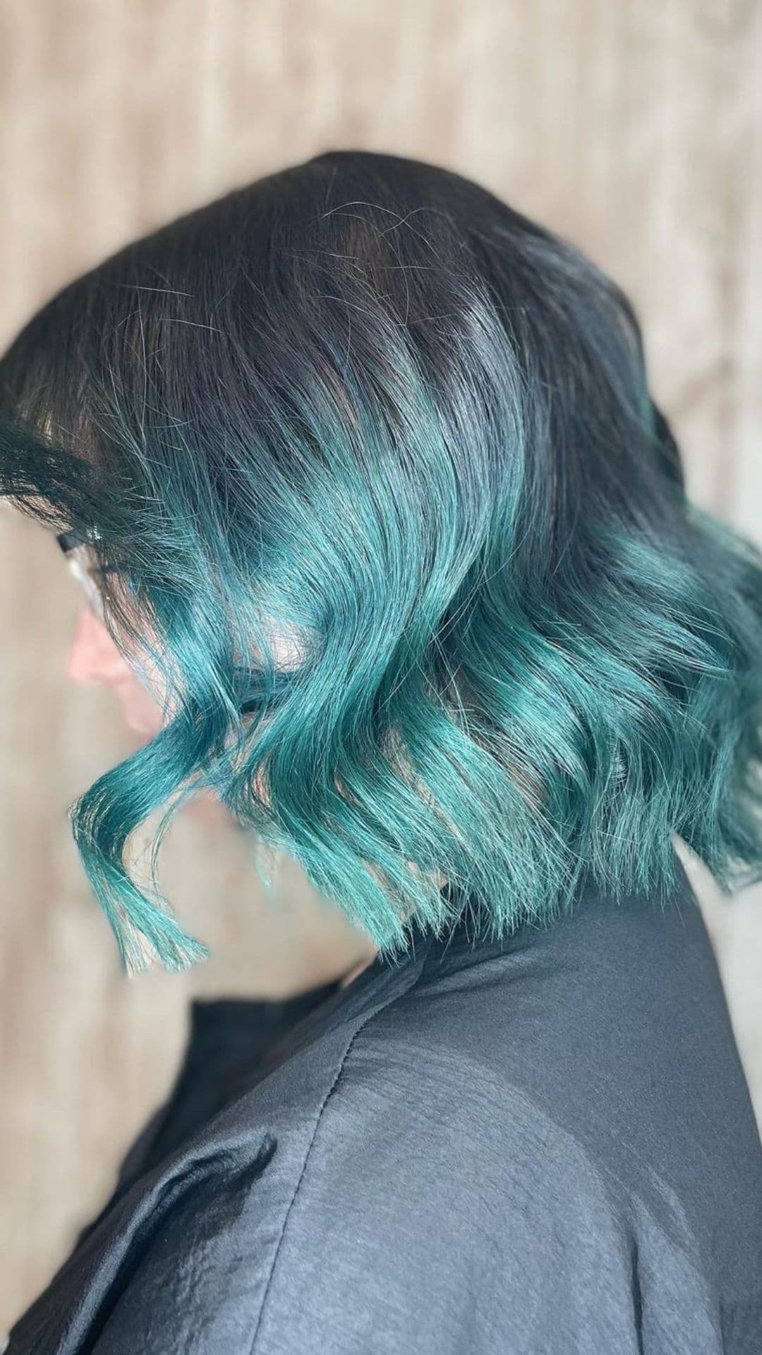 Side view of a person with shoulder-length hair, featuring an Aquamarine Ombre hairstyle that fades from dark roots to vibrant turquoise tips.