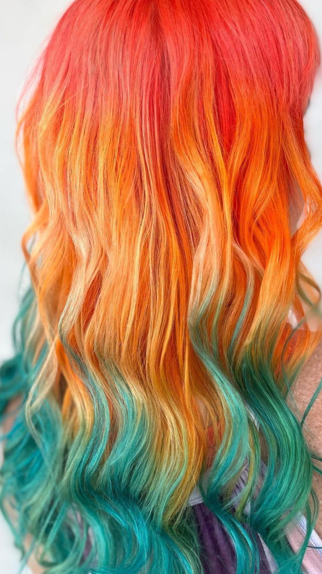 Woman modeling Coral Reef Hair style with vivid red, orange, and teal colors.