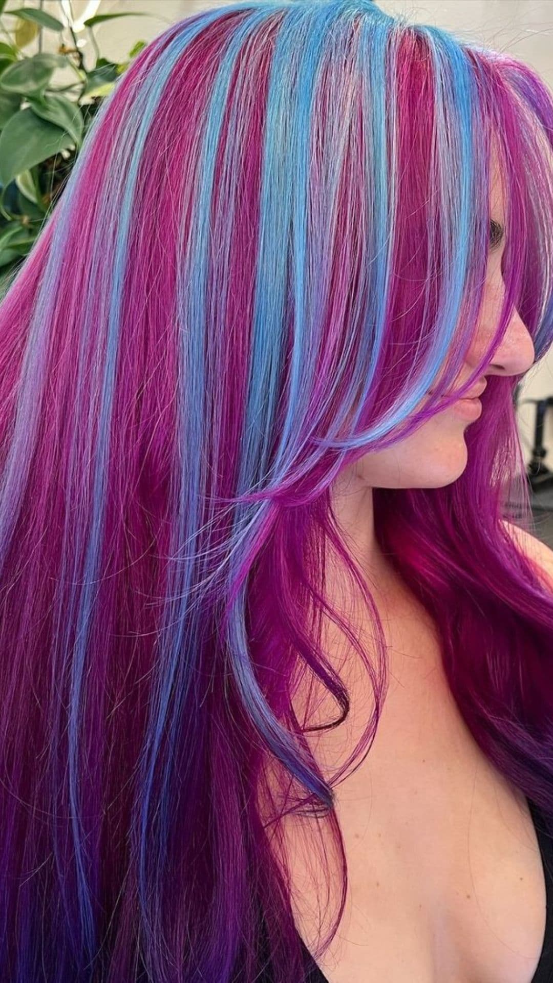 Person with vibrant Dreamy Seaside Purple hairstyle, featuring long hair with alternating purple and blue streaks.