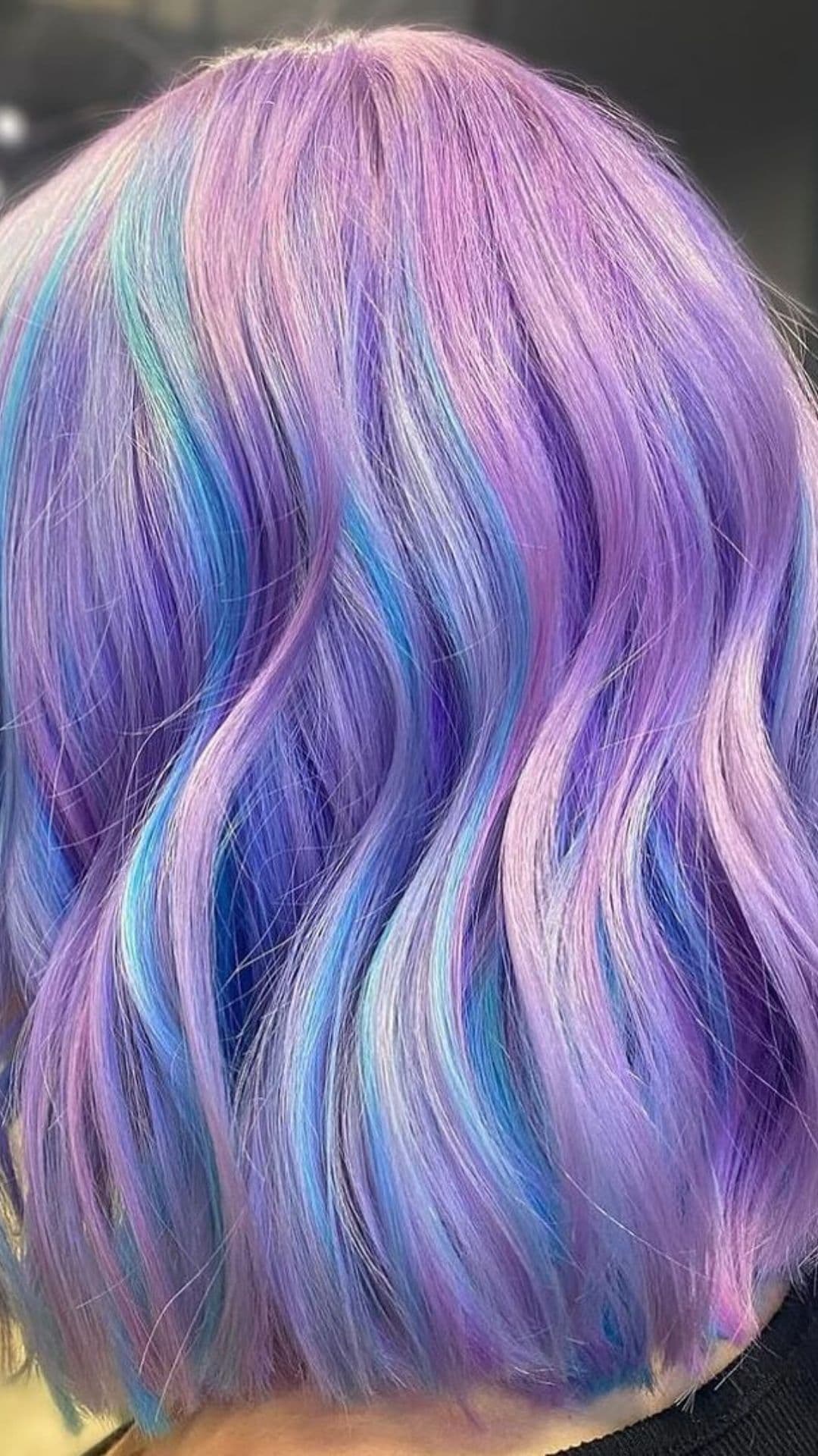 Image of a person modeling Mystical Lavender Locks hairstyle. Their hair displays a blend of lavender and blue tones, styled in soft waves.