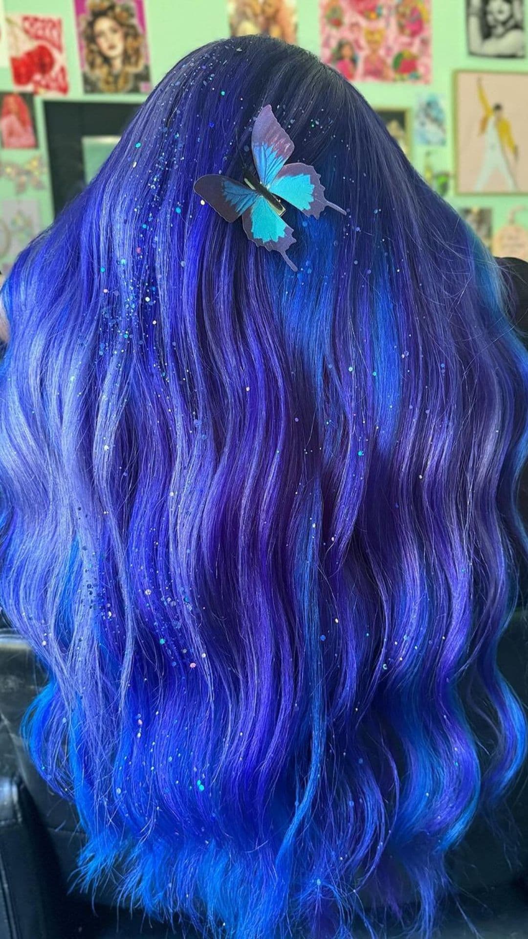 Close-up of a person modeling the Ocean Blue Waves hairstyle. Their hair shows vibrant shades of blue and purple. A butterfly hair clip adds a touch of detail.