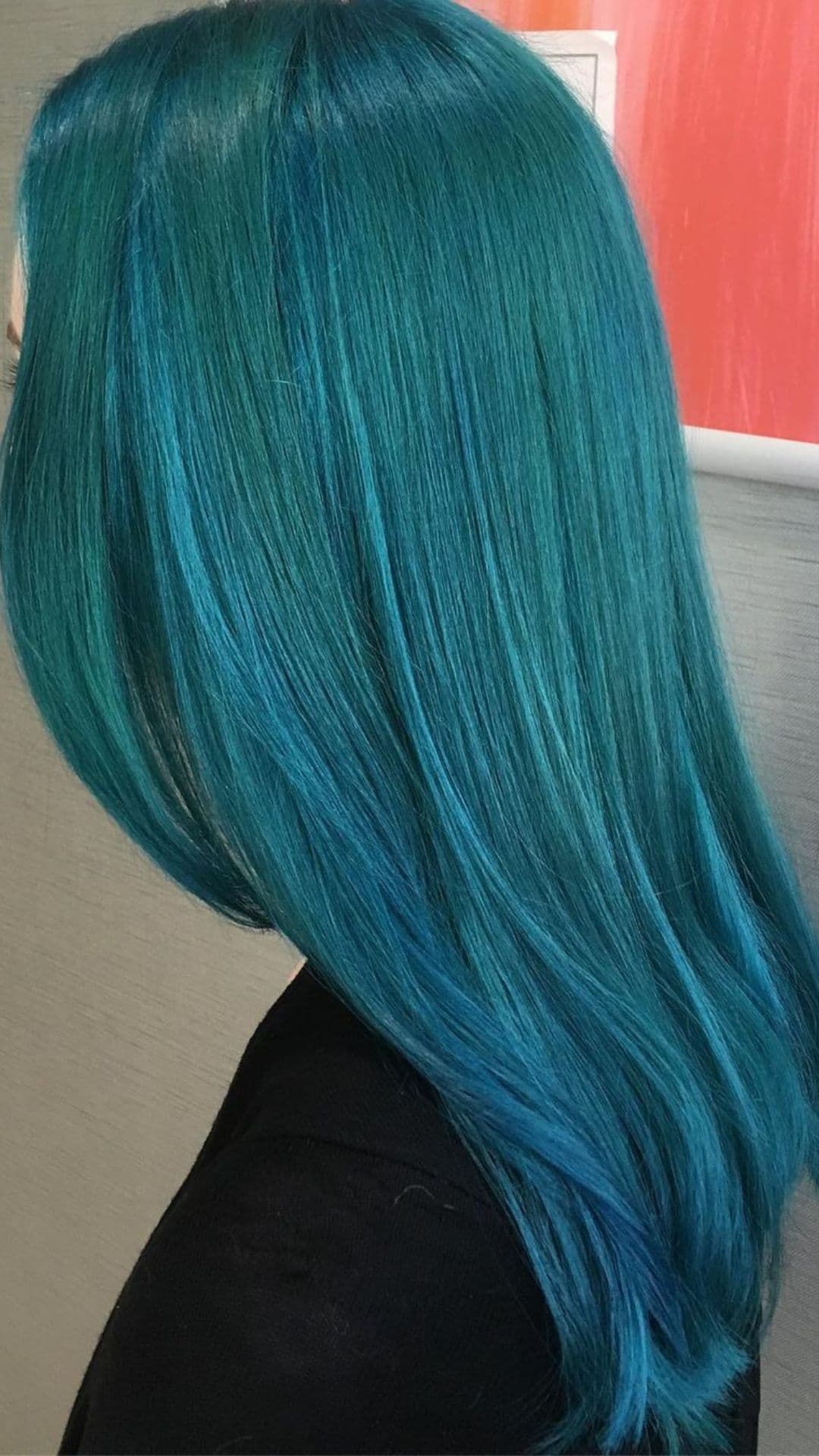 Side view of a person showcasing smooth, long teal and turquoise hair.