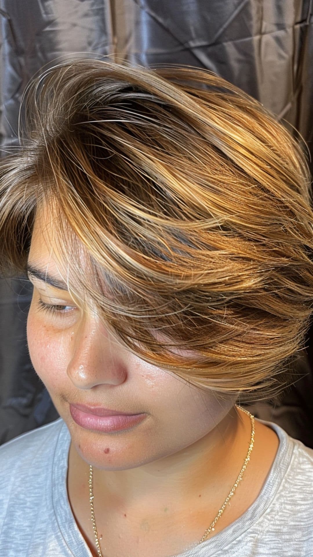 A woman modelling a mocha blonde balayage feathered bixie cut.