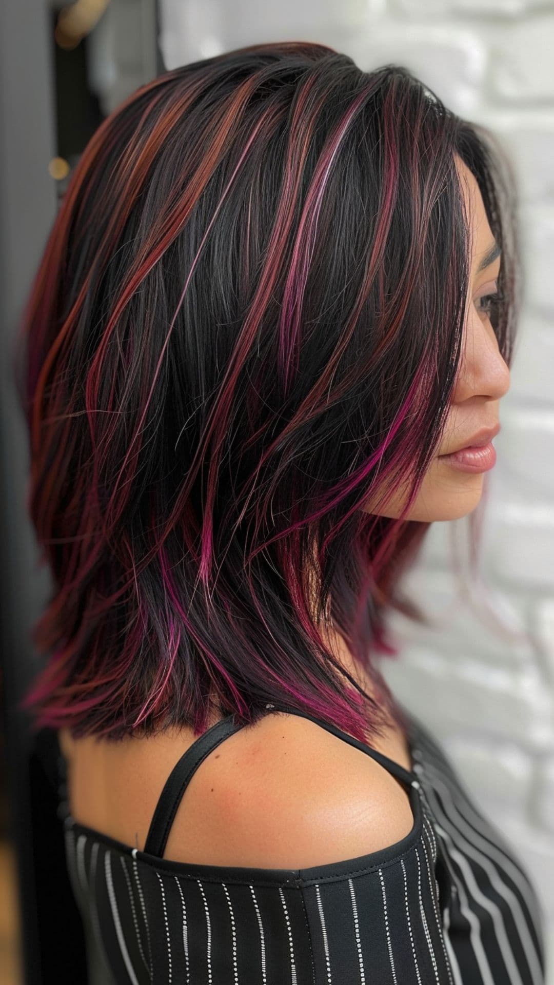 A woman modelling a black hair with pink highlights.