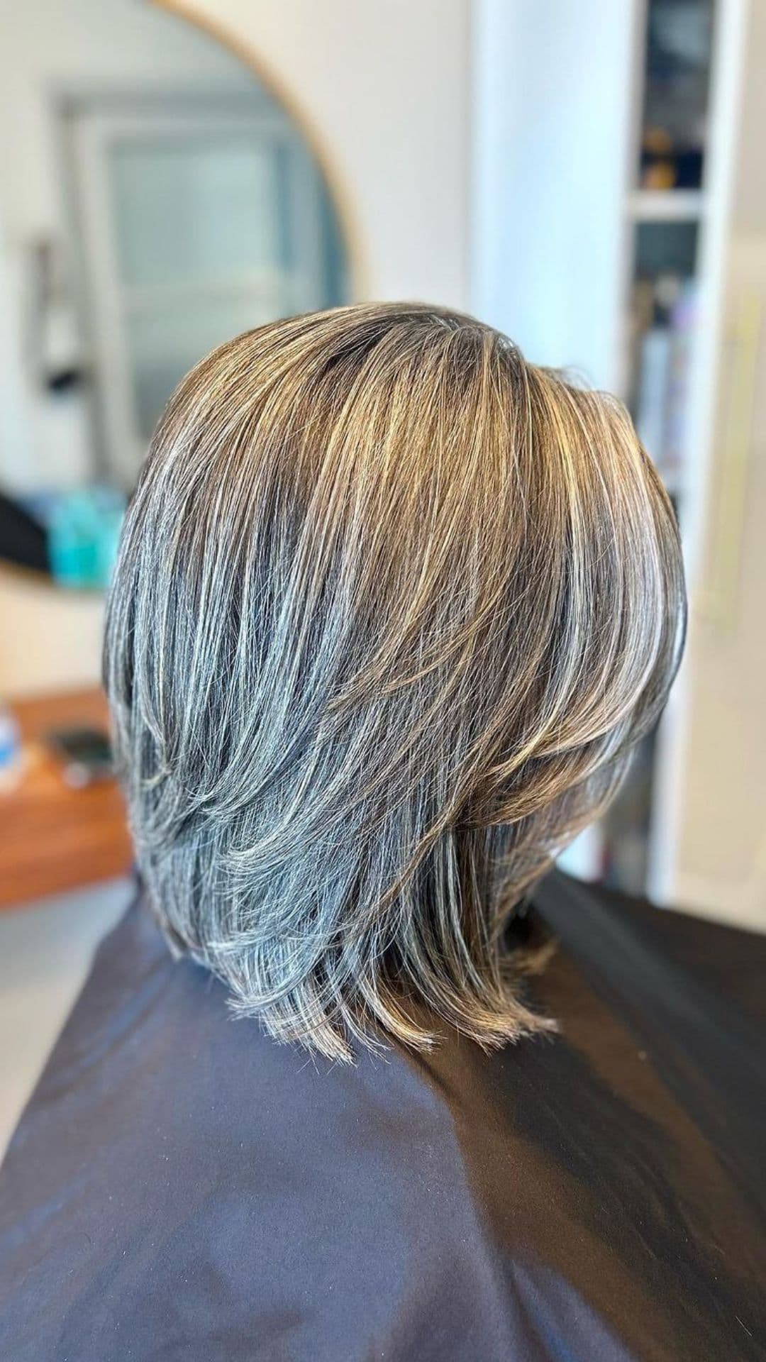 An older woman modelling a short layered salt and pepper haircut.