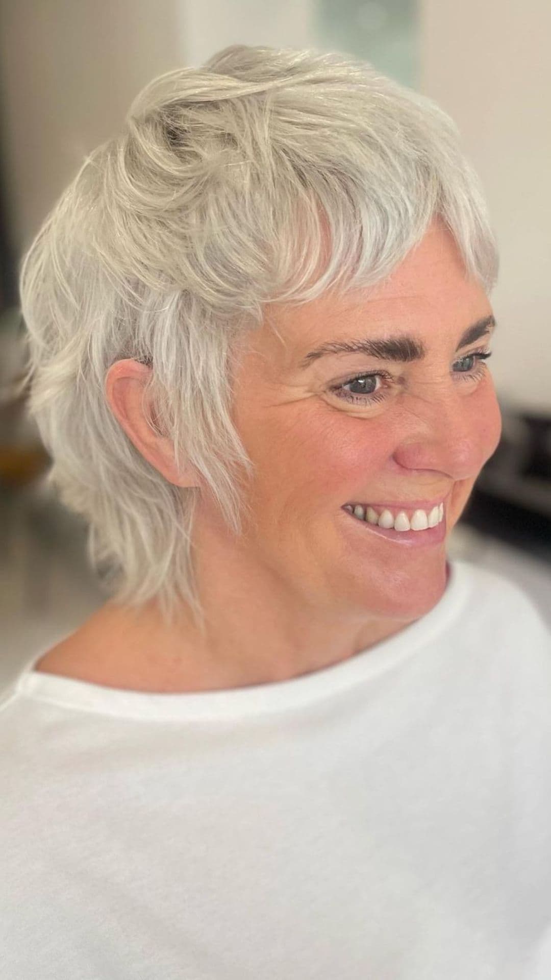 An older woman modelling a short platinum mullet hairstyle.