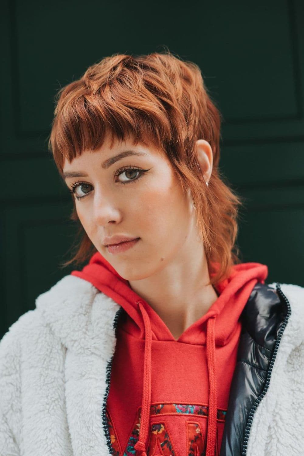 A woman with a brown, short, razored wolf cut.