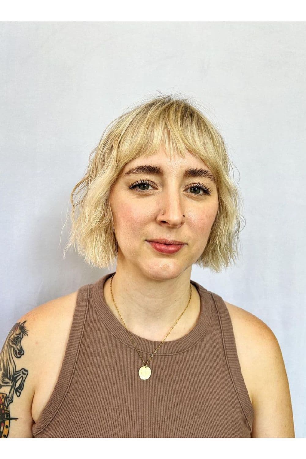 A woman with short wavy blonde hair with baby bangs.