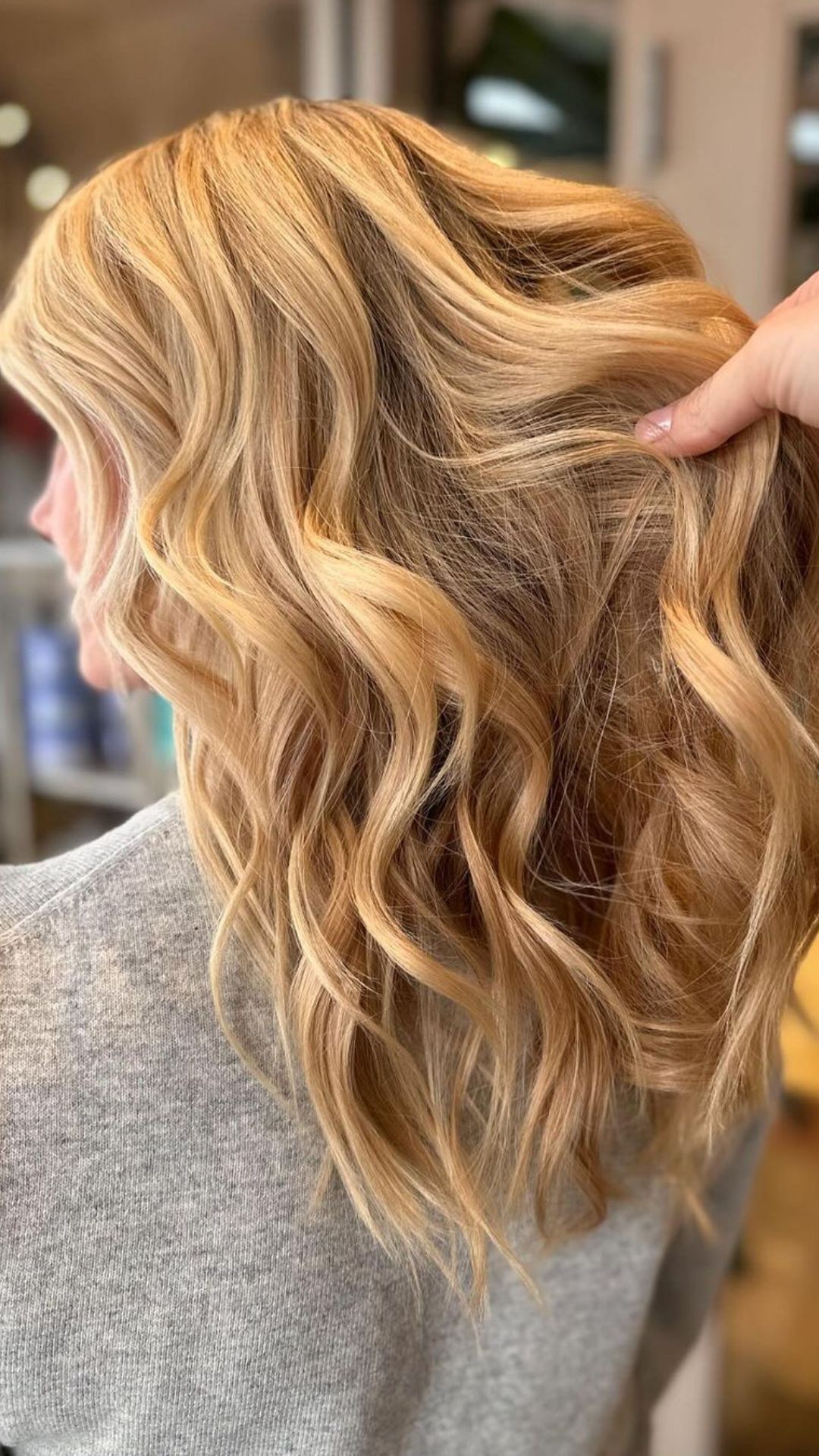 Close-up of a person with wavy Bombshell Blonde hair, styled beautifully.