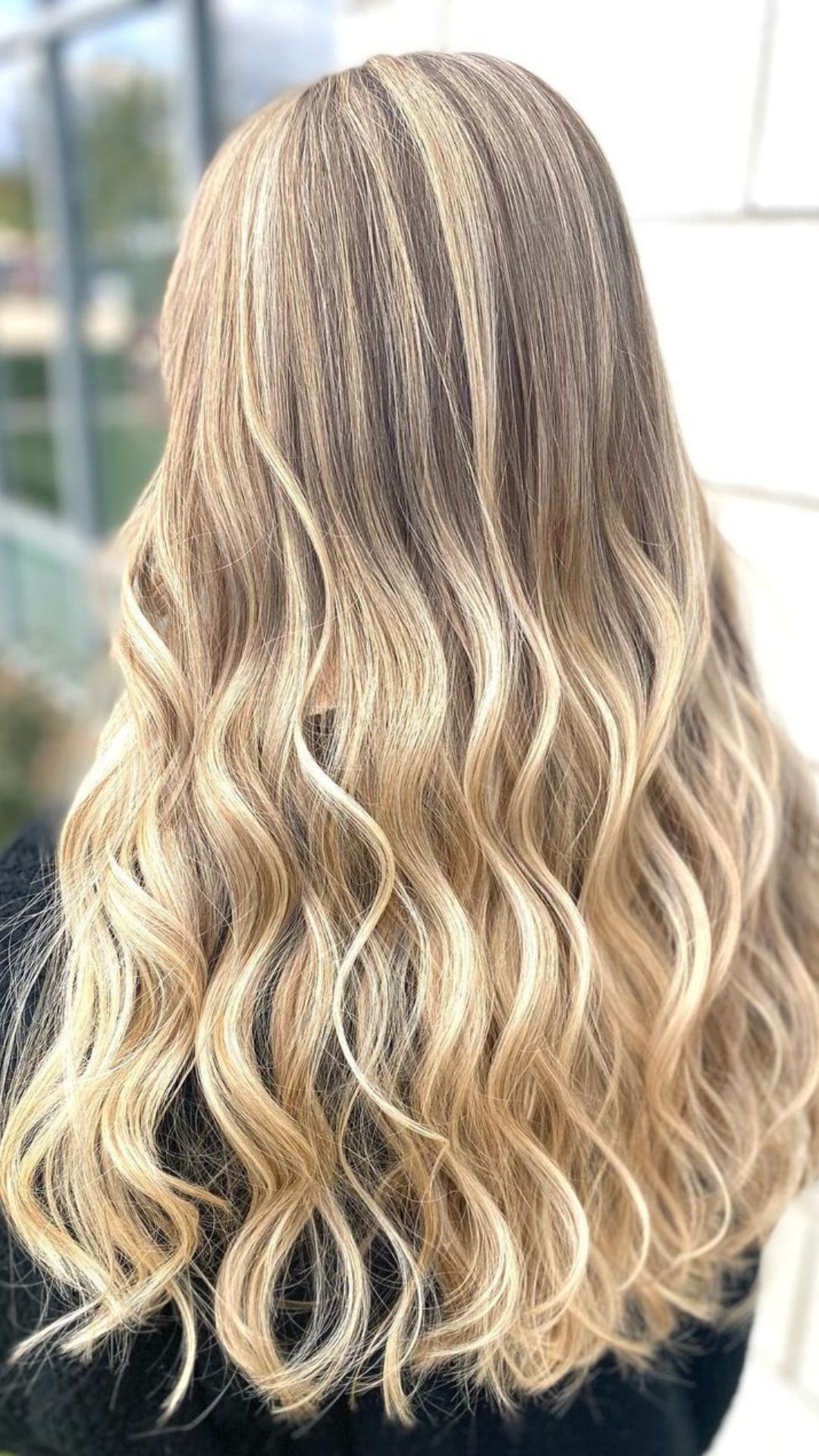 Person with long, wavy hair showing the Buttercream Blonde style. The hair has a mix of warm and cool tones, providing a soft, natural appearance.