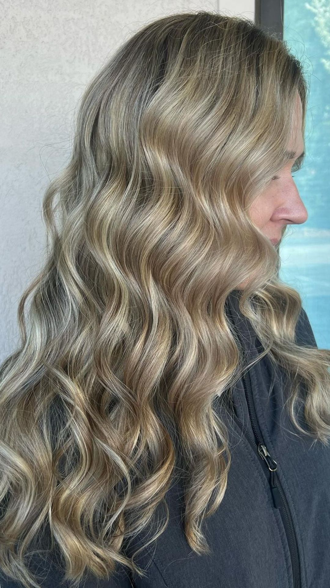 Profile of a person with a Butterscotch Blonde hairstyle, featuring long, loose waves.