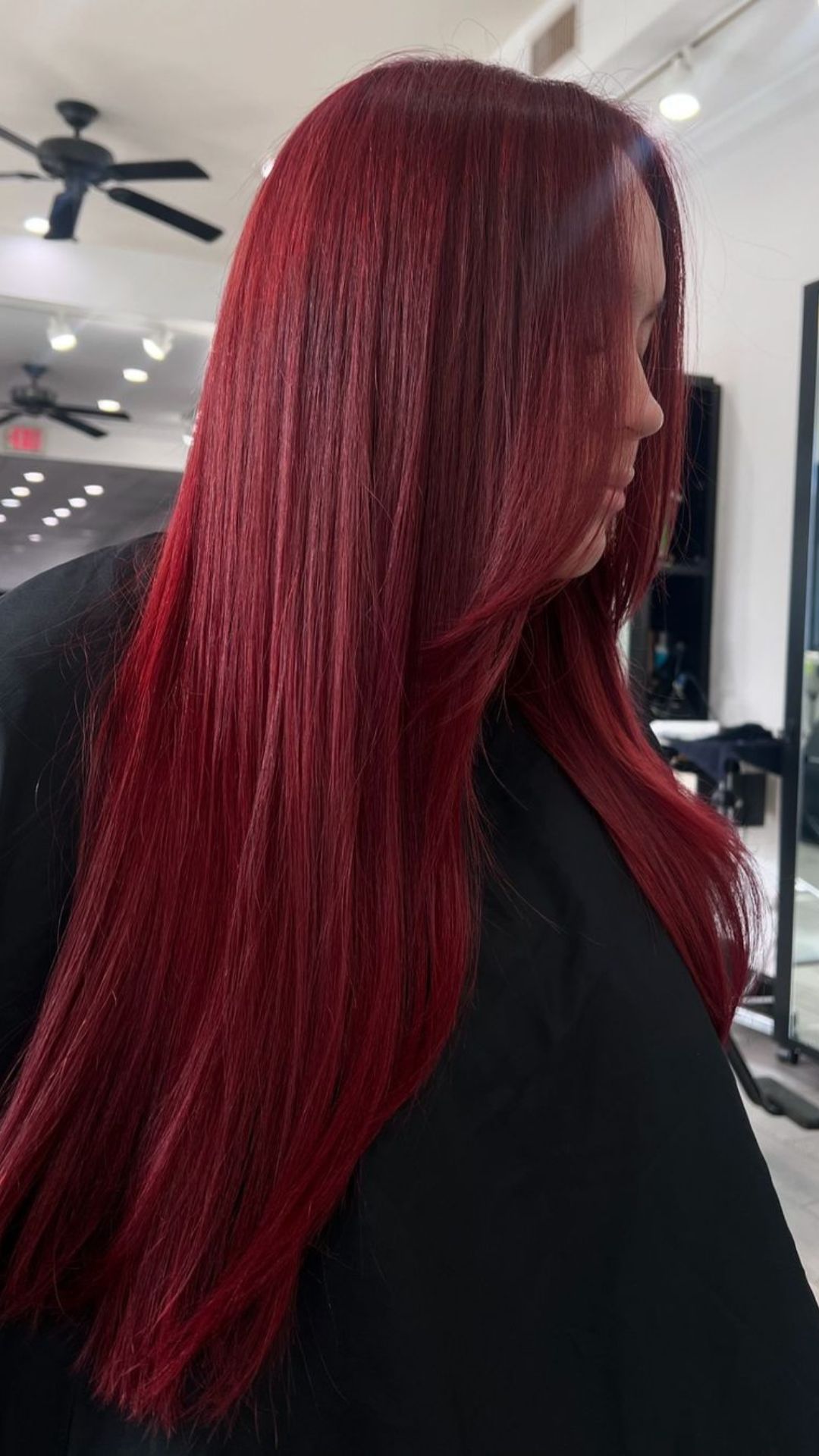 A person with long, straight Eternal Red hair, showcased in a salon setting.