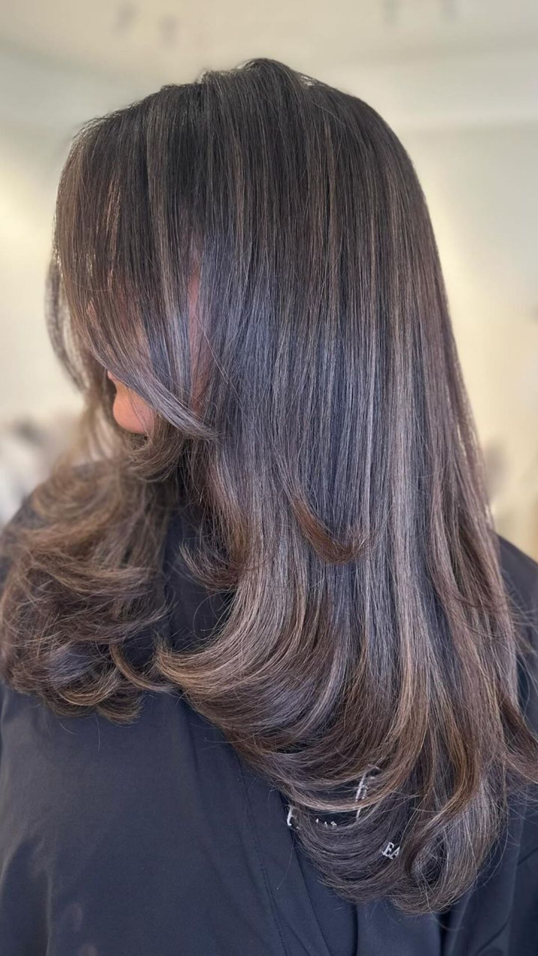 Woman showcasing Expensive Brunette hairstyle with smooth waves and polished finish.