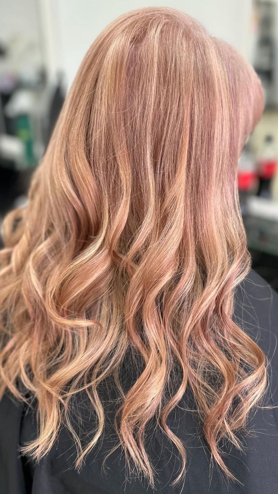 Close-up of someone with long wavy hair in a rose gold shade.