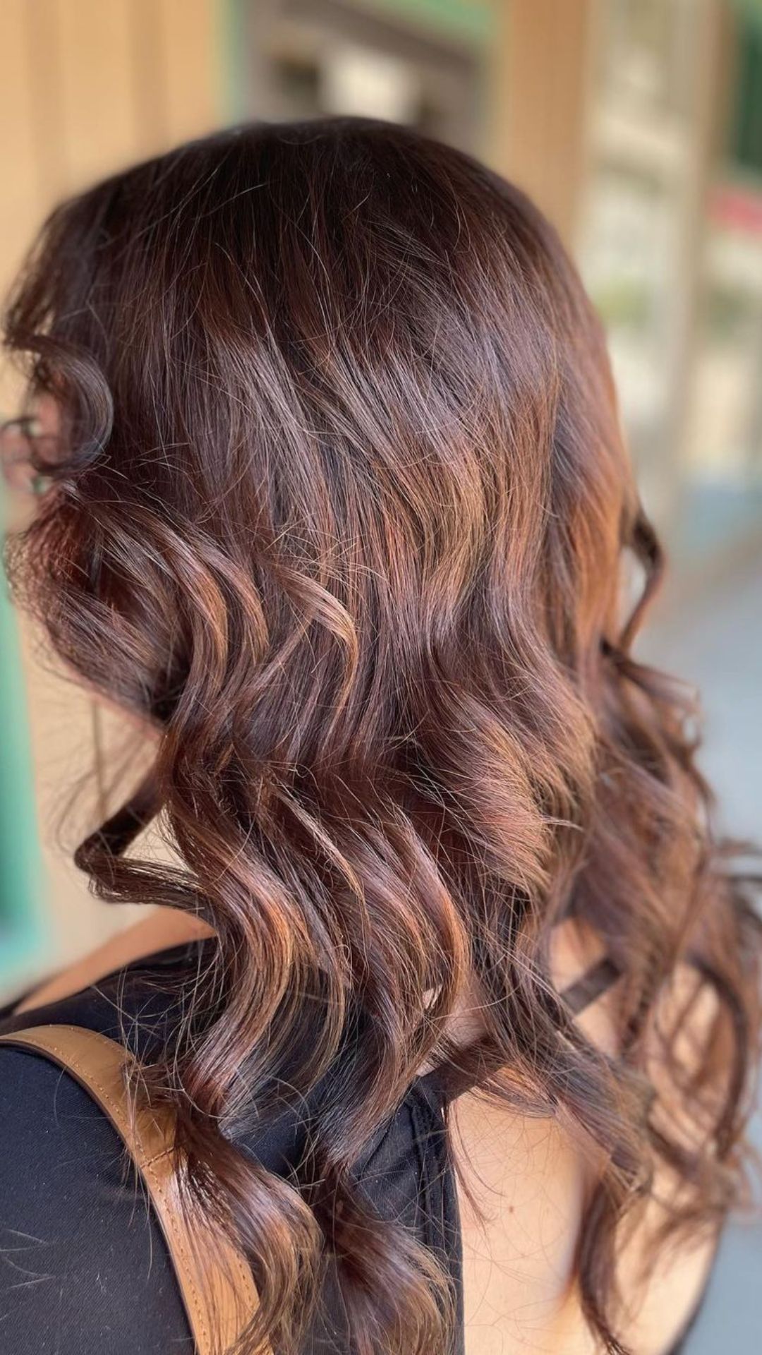 Woman with wavy strawberry brunette hair seen from behind, wearing a black top.