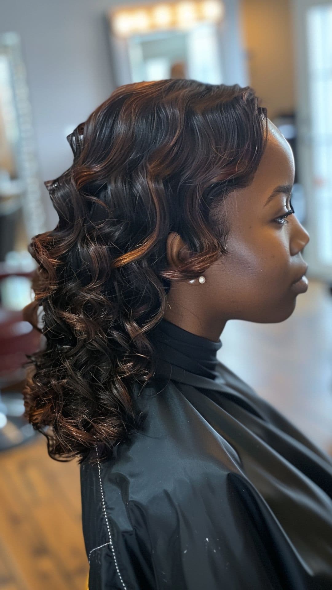 A woman modelling a black curly hair with honey brown highlights.