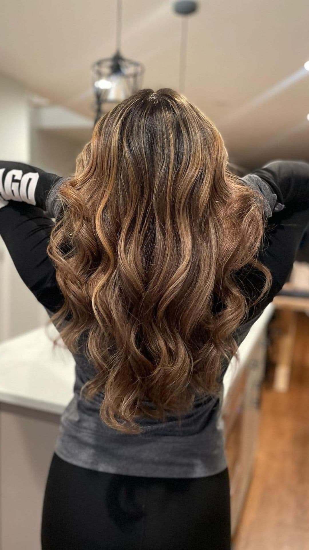 Person with long, wavy hair featuring a Chocolate and Caramel Ribboning hairstyle, seen from the back.