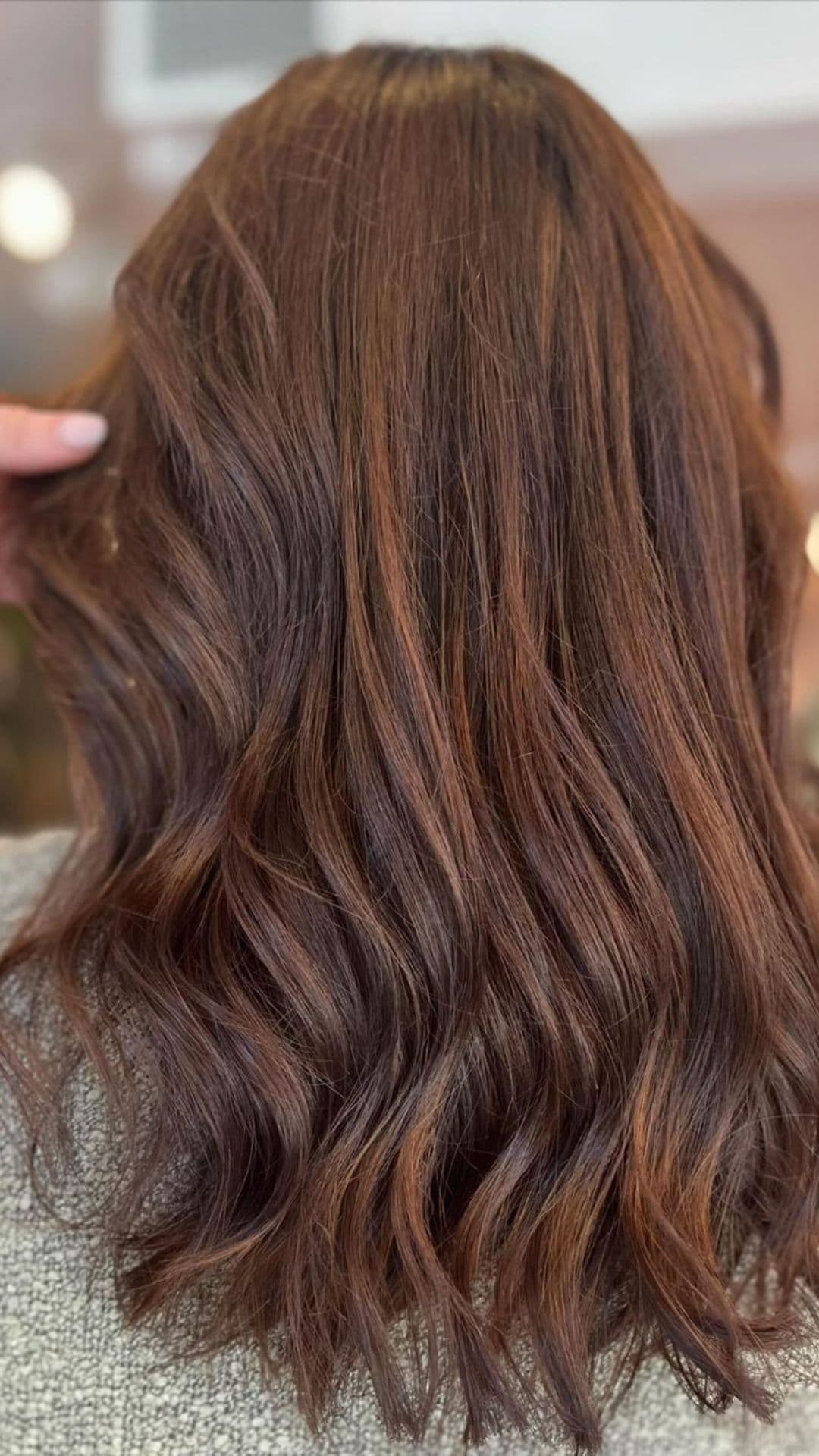 Close-up of hazelnut highlights hairstyle with soft waves and a natural finish.