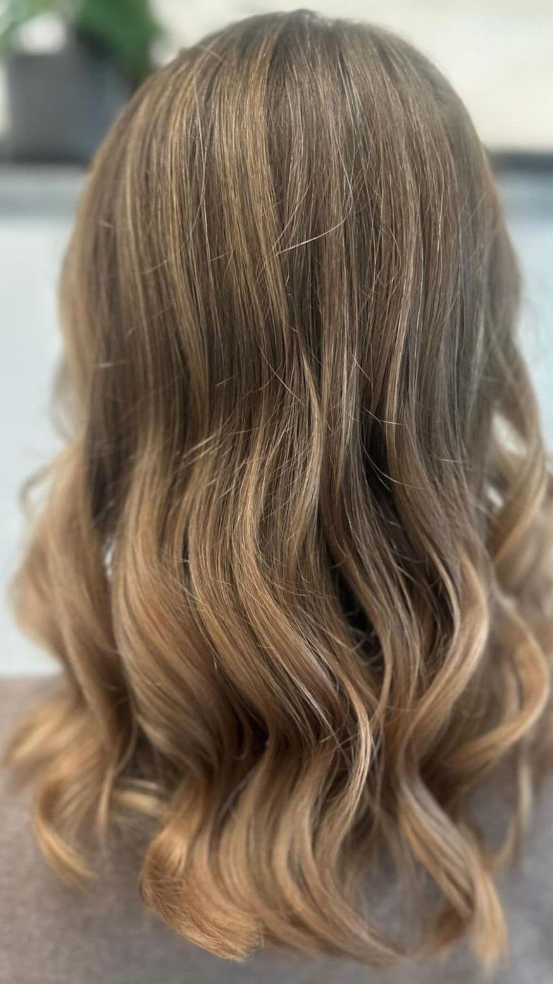 Back view of long hair with a sandy brown color and soft waves.